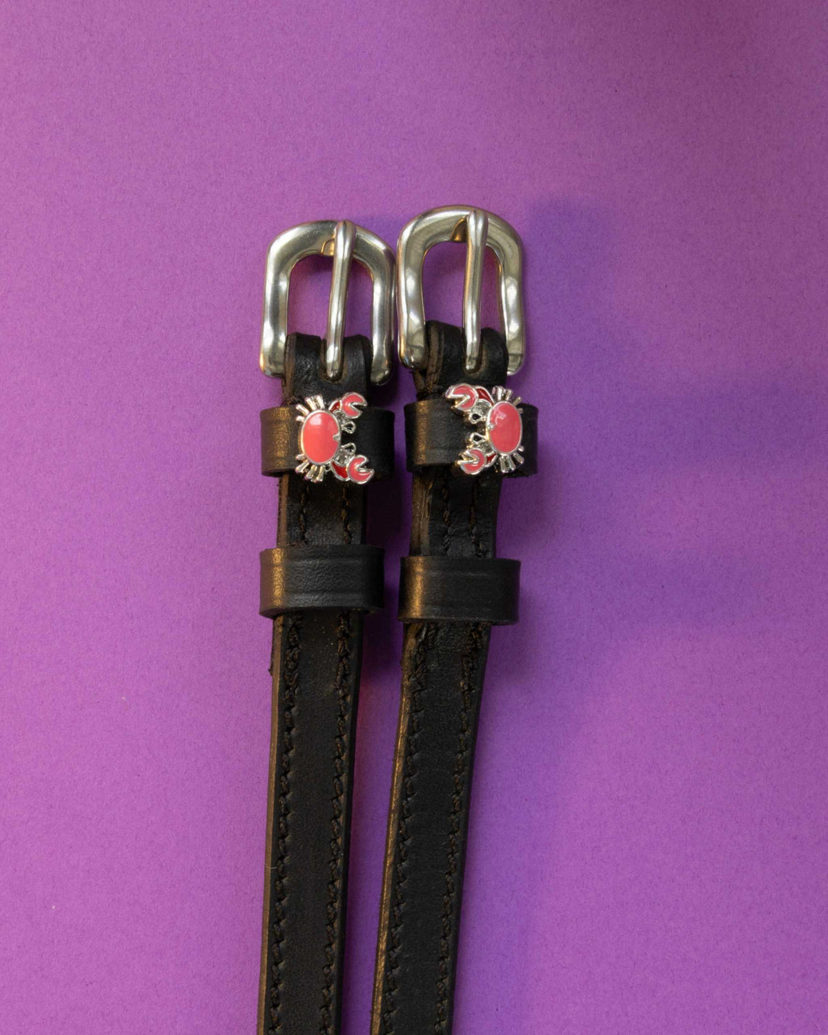 Crabbin' ManeJane spur straps with the signature Crabbin' charm, shown on a purple background