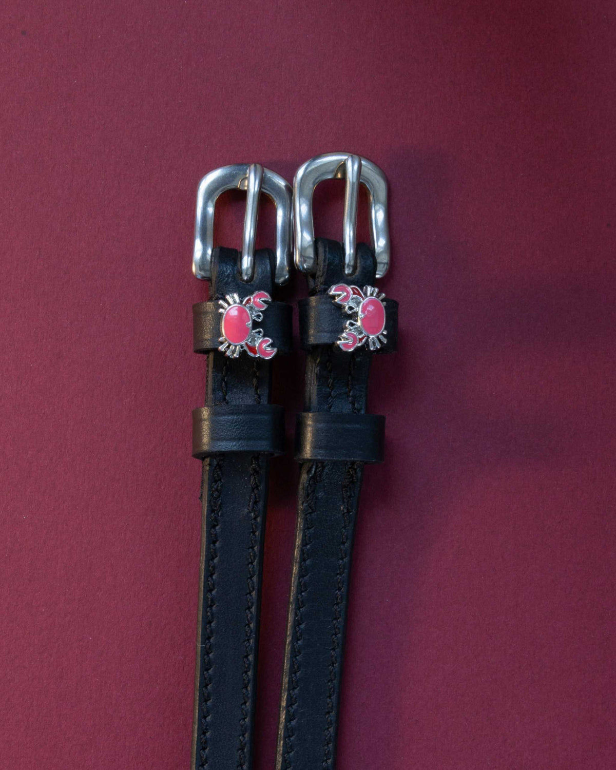 Crabbin' ManeJane spur straps with the signature Crabbin' charm, shown on a plum background