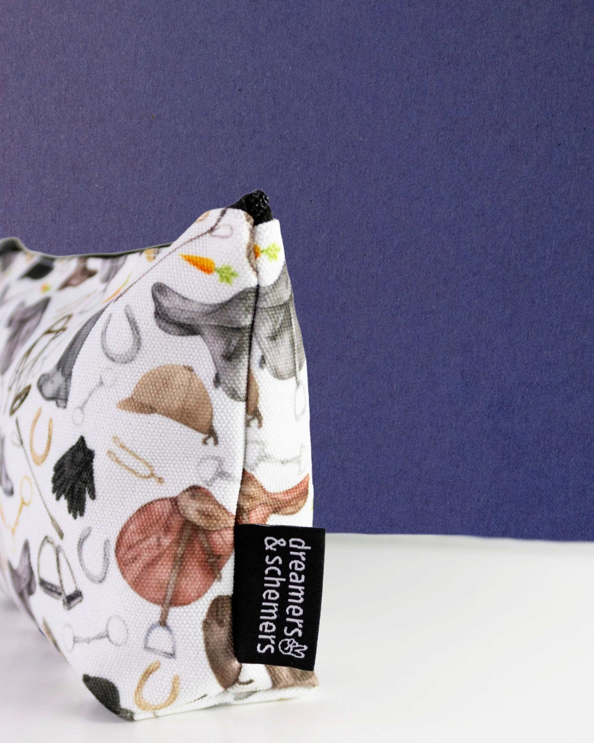 The Hunt zip pouch standing on its gusset, showing the side panel and the woven dreamers & schemers tag