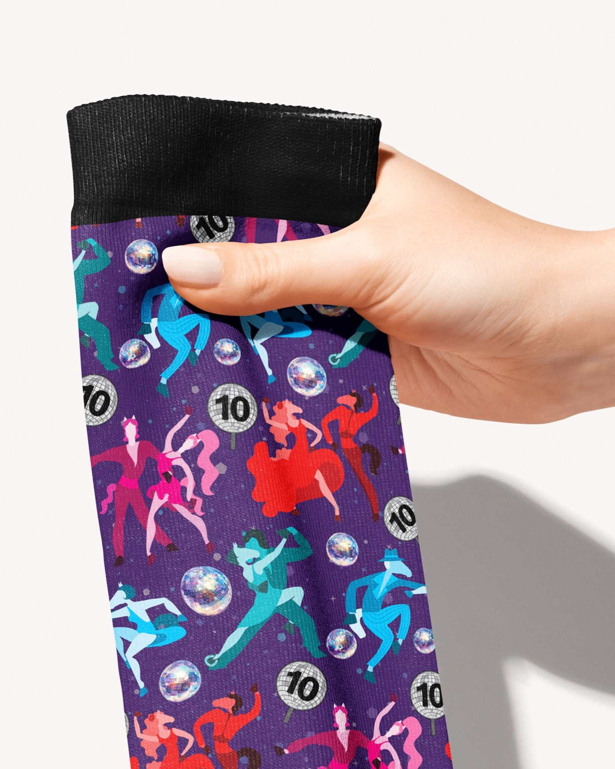 Prancing with the Stars Limited Edition boot socks, dancing couples and disco balls on deep purple, held in hand, close-up of the print, by Dreamers & Schemers