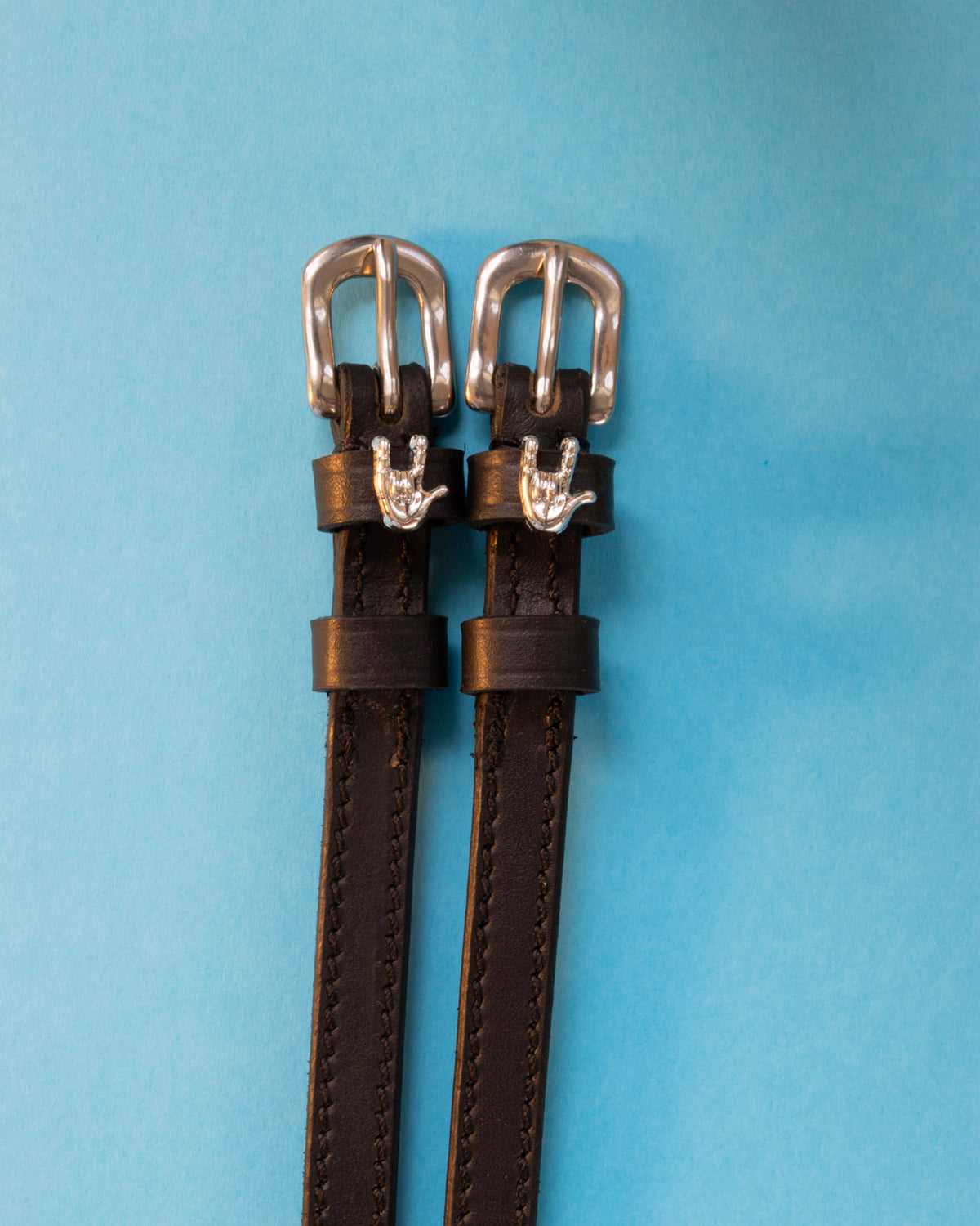 Rock On ManeJane spur straps with the signature Rock On charm, shown on a light blue background