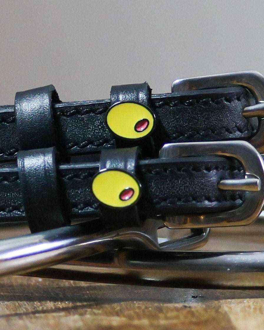 Black leather Spur Straps with stainless steel buckles and custom yellow charm close-up