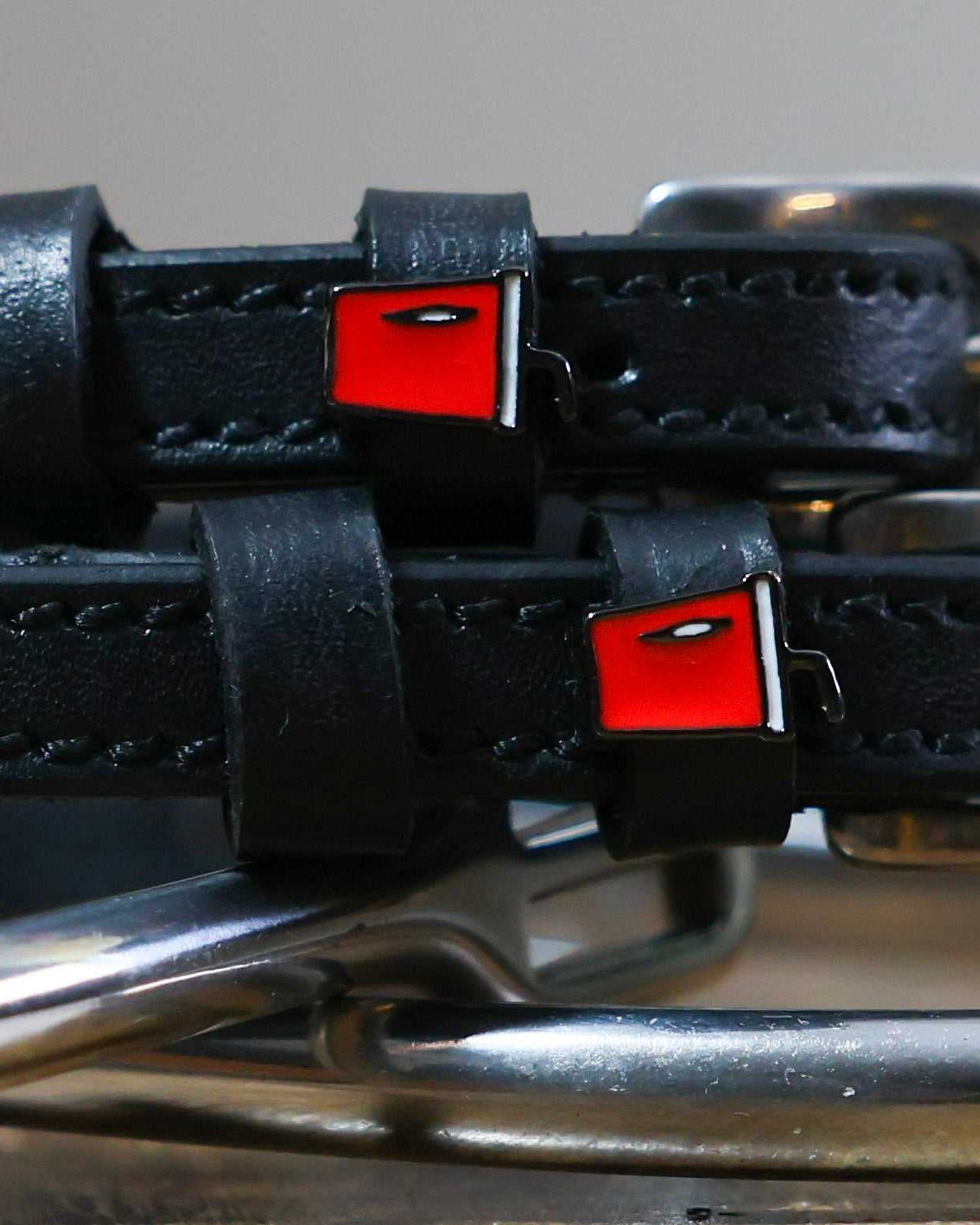 Black leather Soda Spur Straps with stainless steel buckles and red custom charms on horse spurs