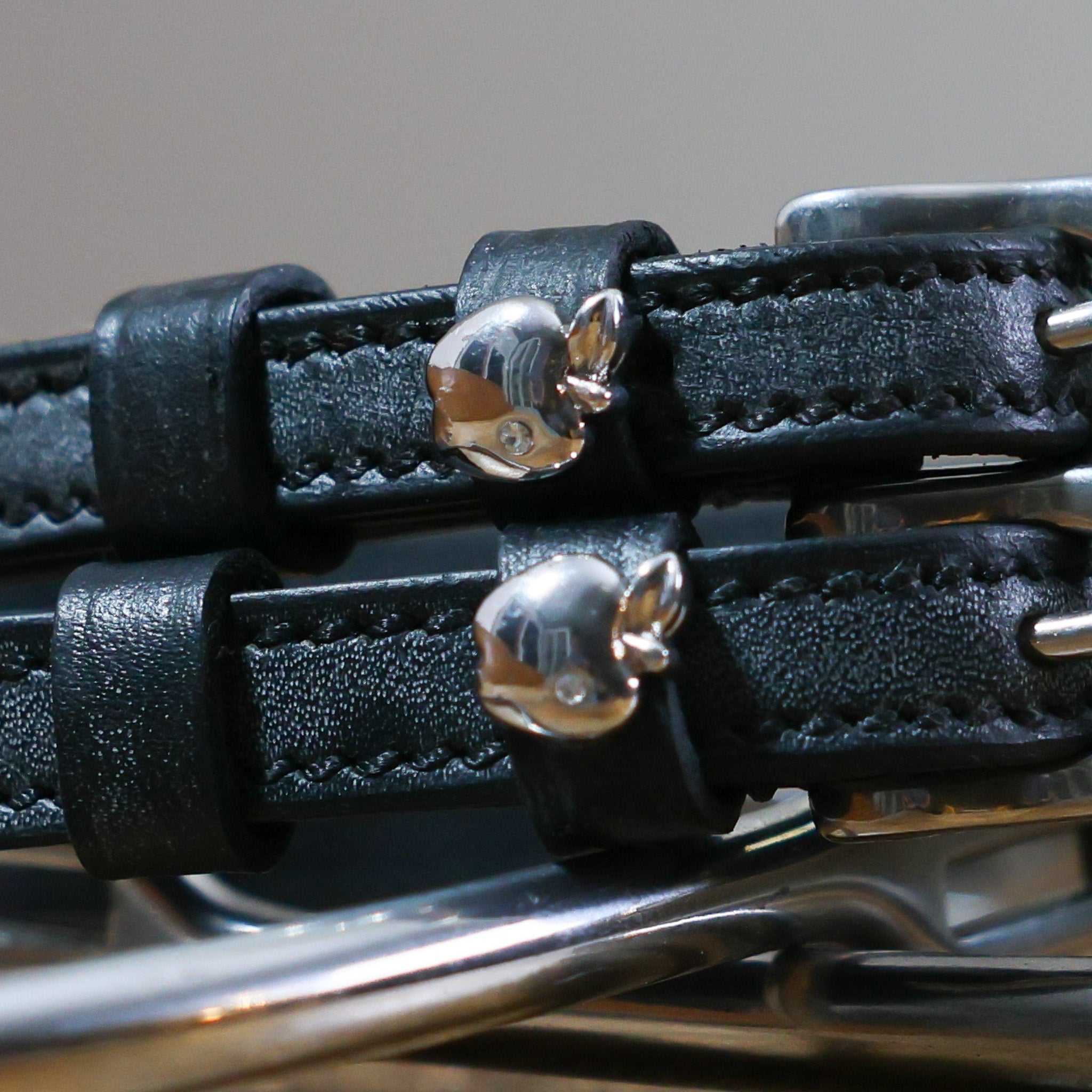 Close-up of black leather Silver Apple Spur Straps with shiny silver apple charms and stainless steel buckles.