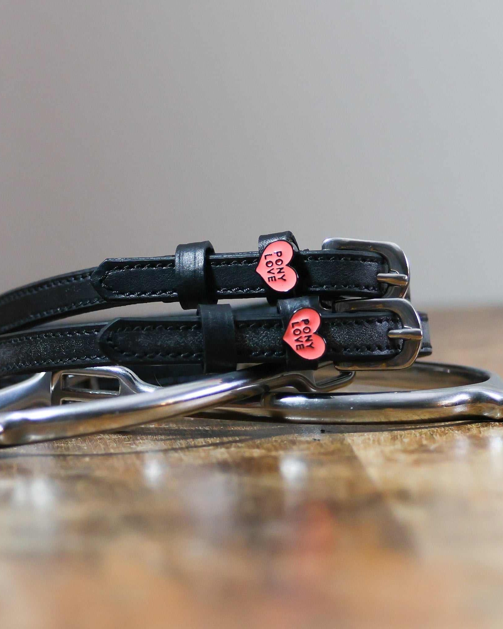 Black leather Pony Love Spur Straps with stainless steel buckles and heart-shaped charms