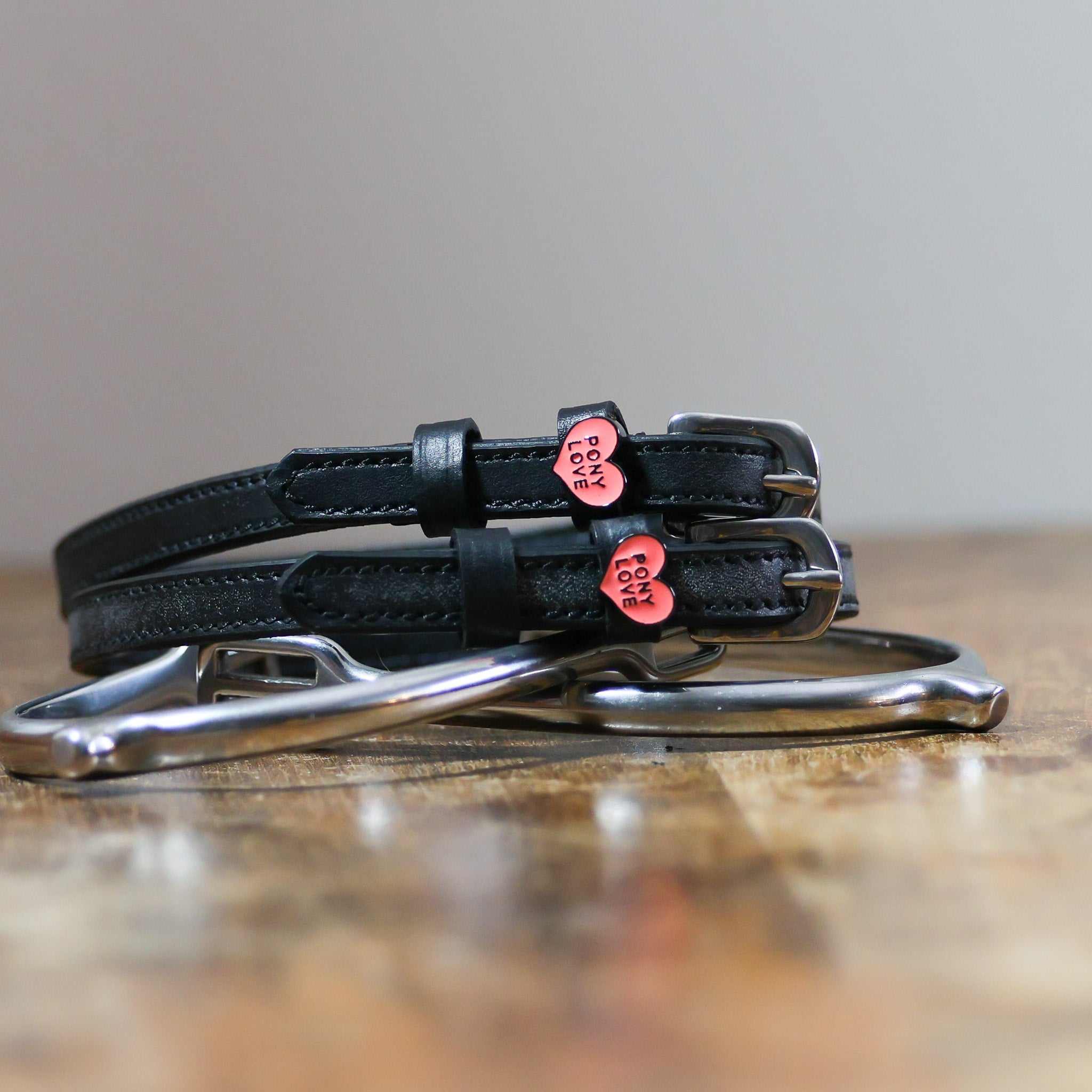 Black leather Pony Love Spur Straps with stainless steel buckles and heart-shaped charms