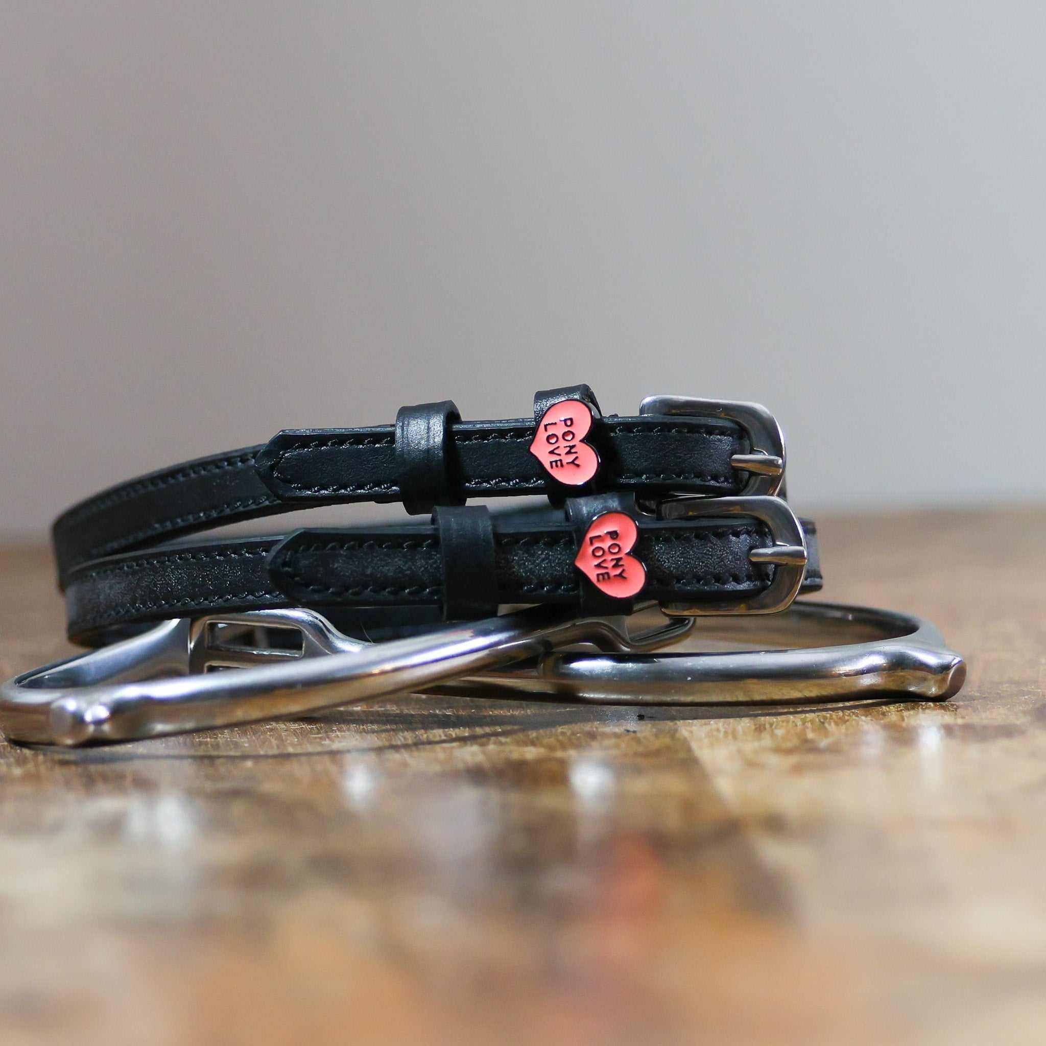 Black leather Pony Love Spur Straps with stainless steel buckles and heart-shaped charms