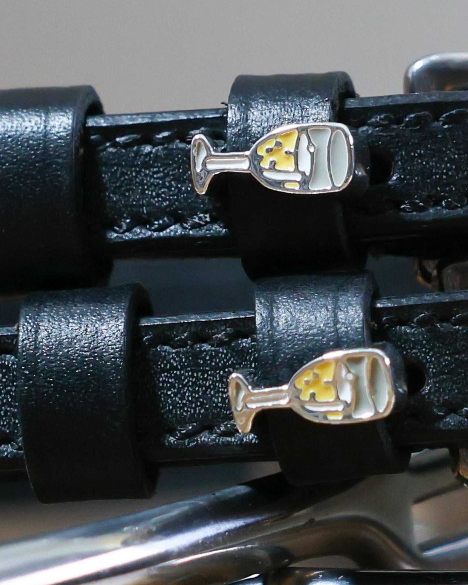 Close-up of black leather Champagne Spur Straps with stainless steel buckles and custom champagne glass charms