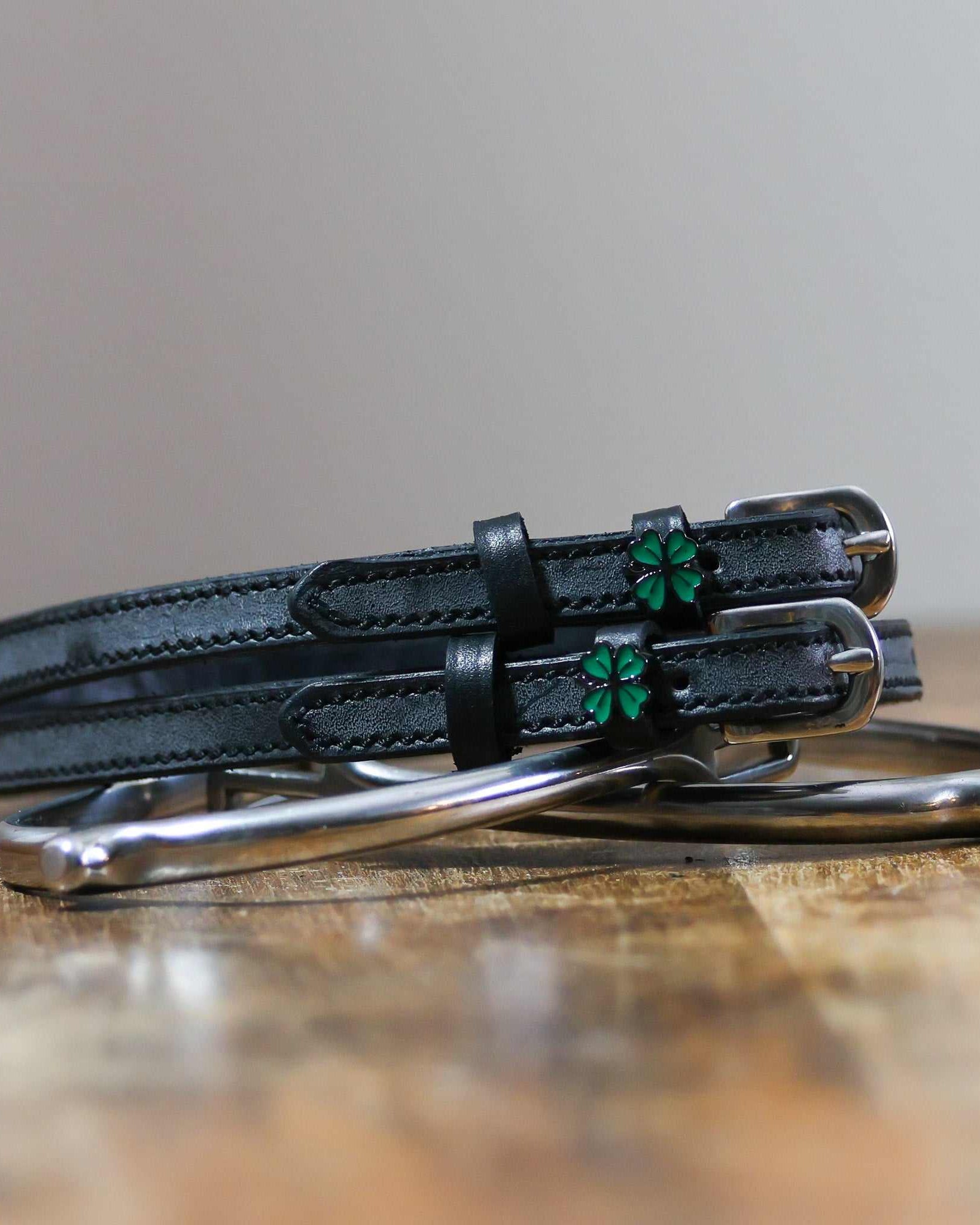 Four-leaf clover spur straps from Lucky Equestrian Bundle on wooden surface