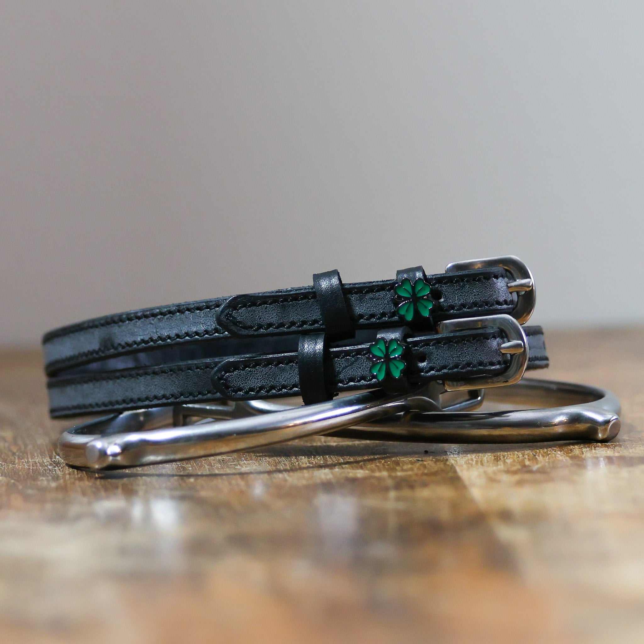 Four-leaf clover spur straps from Lucky Equestrian Bundle on wooden surface