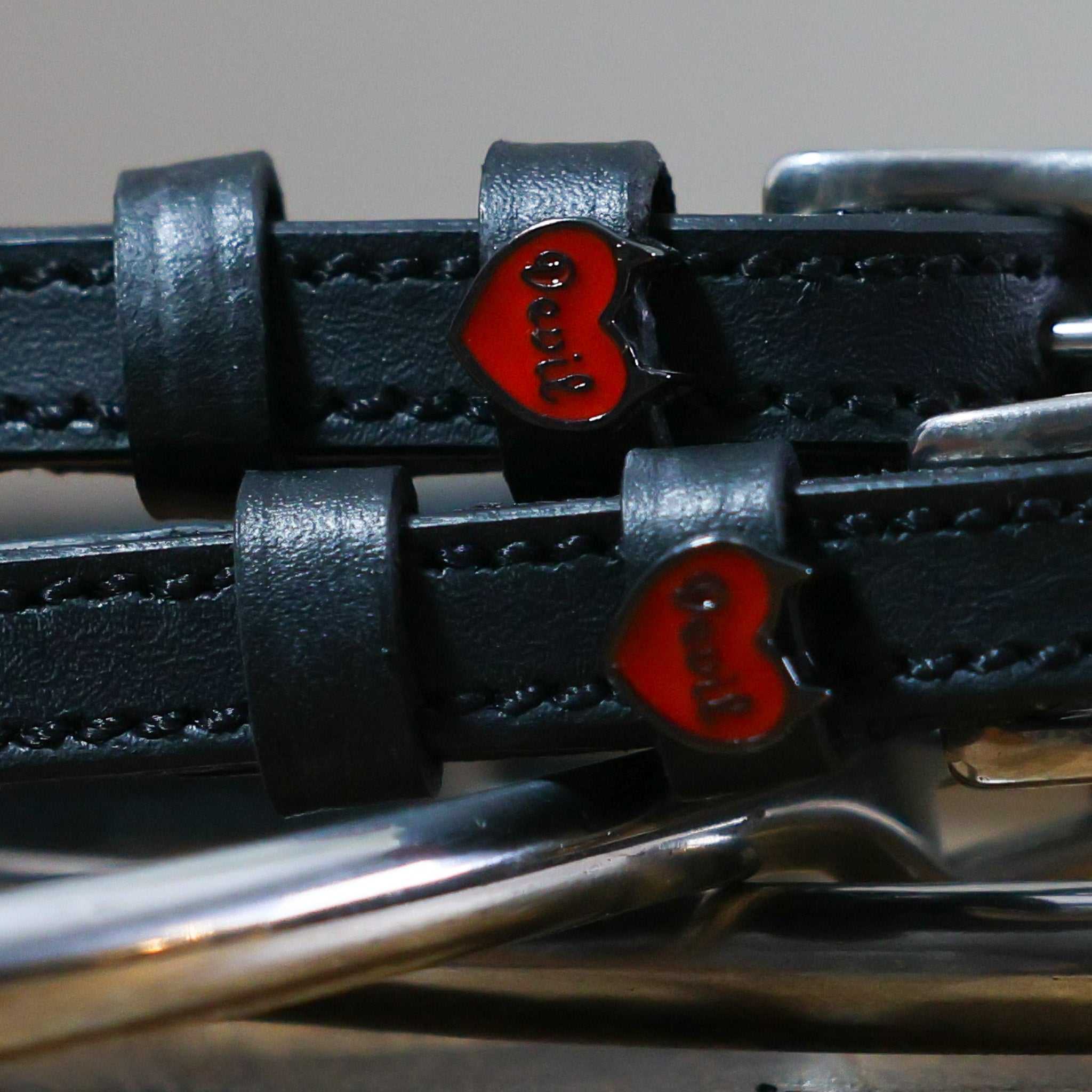 Black leather Devil Heart Spur Straps with red heart charm and stainless steel buckle close-up