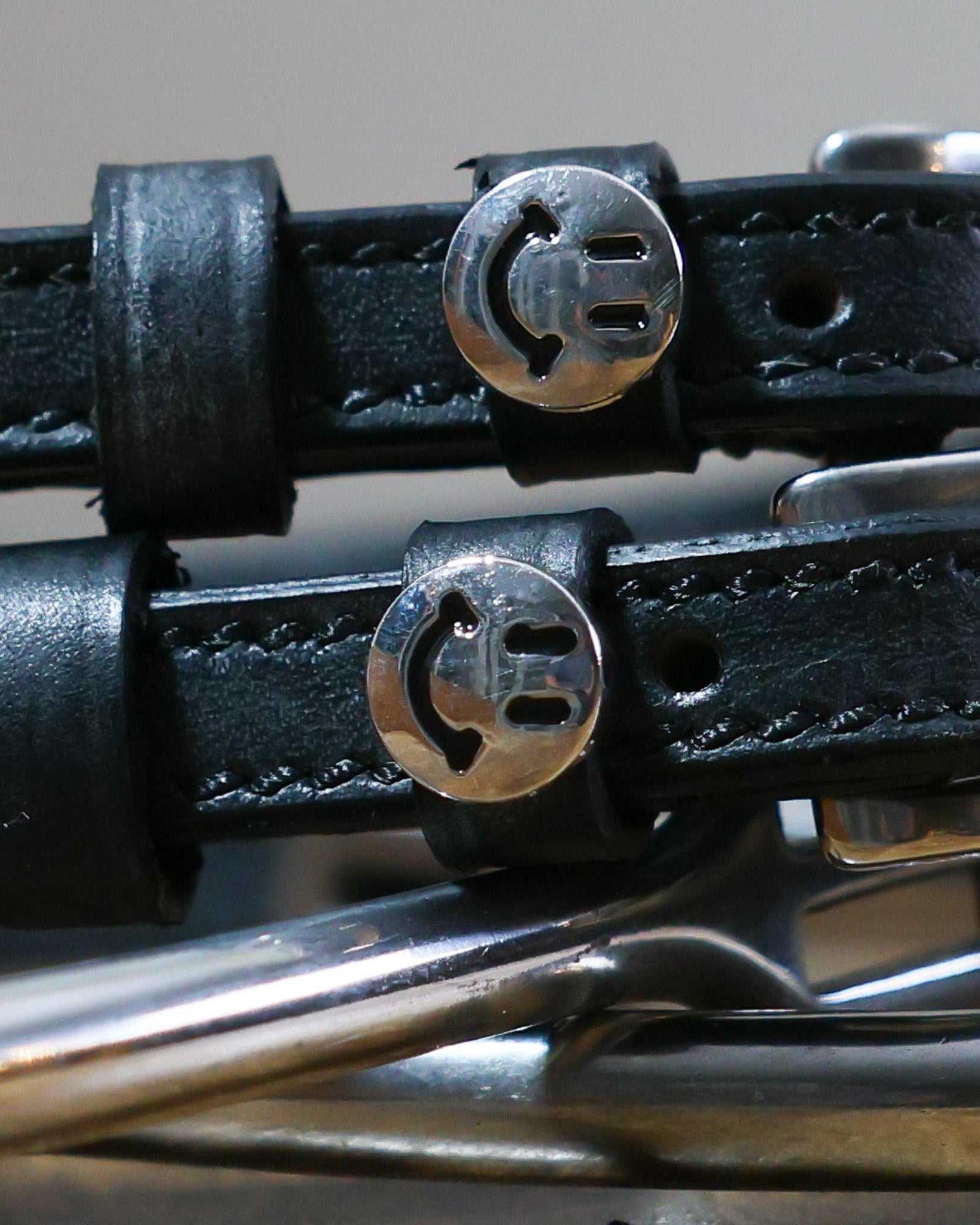 Close-up of black leather Happy Face Spur Straps with stainless steel smiley face charm and buckle
