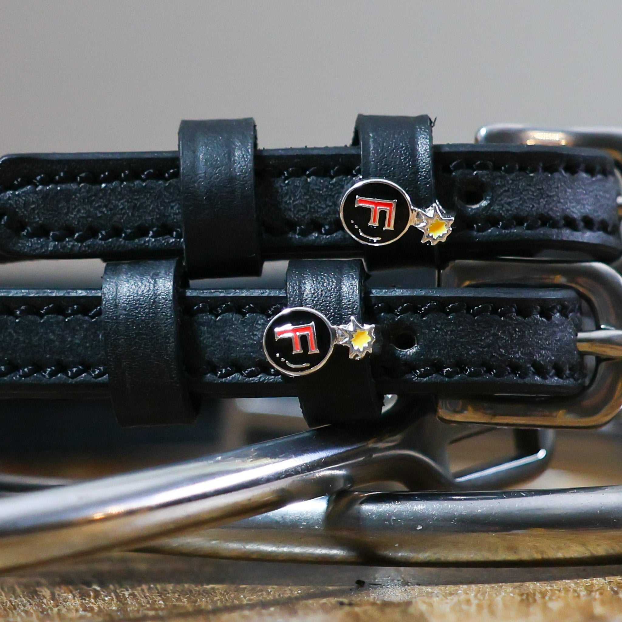 Black leather F Bomb spur straps with stainless steel buckles and custom charms on metal spurs
