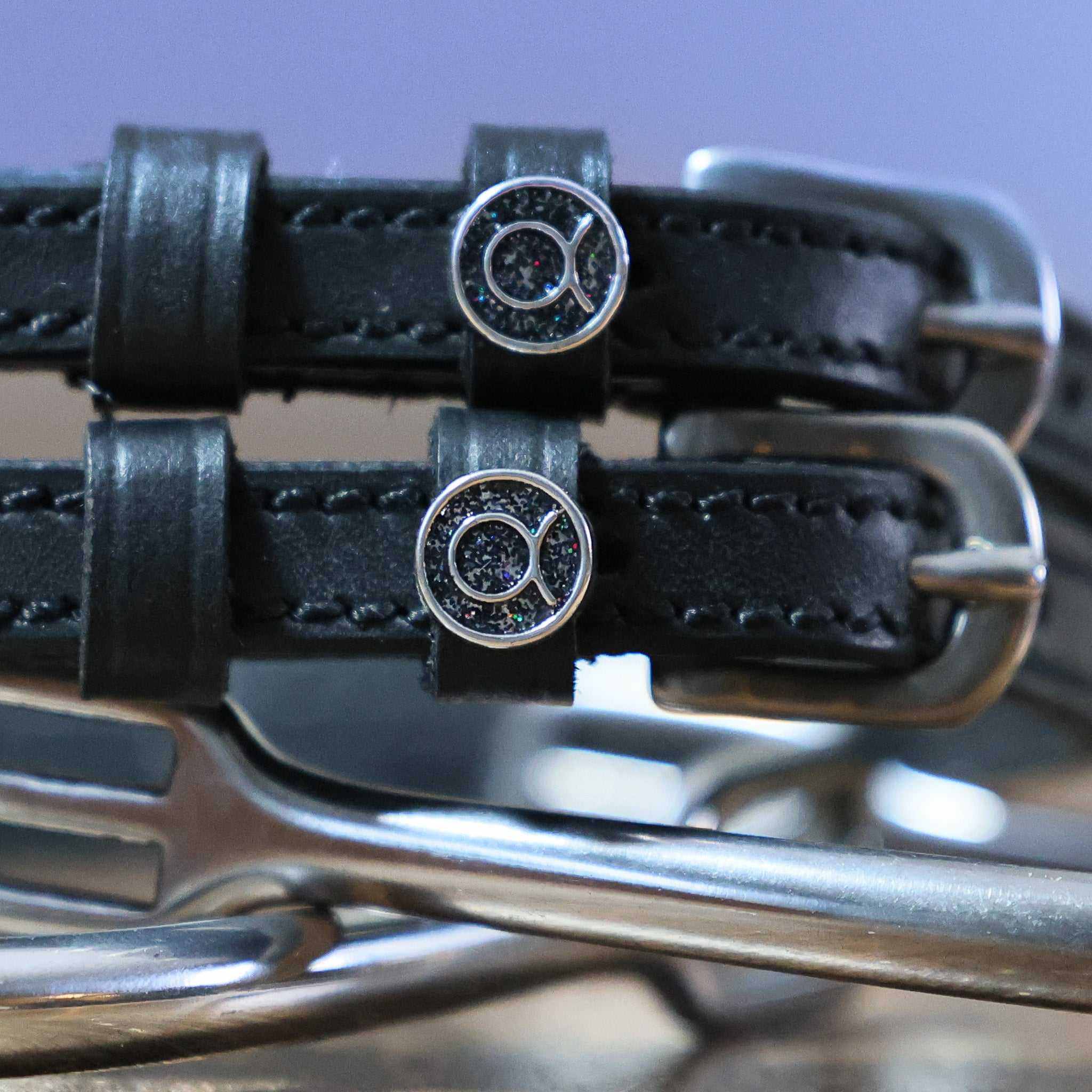 Close-up of black leather Taurus Spur Straps with stainless steel buckles and custom charm on metal spurs