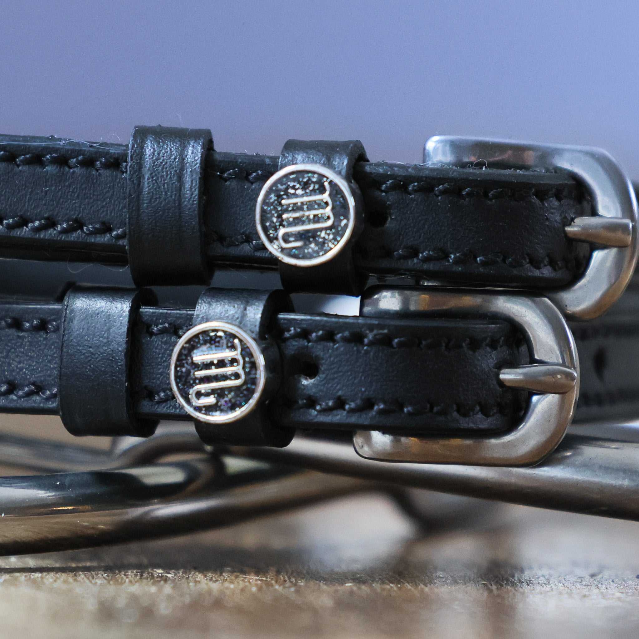 Close-up of black leather Scorpio Spur Straps with stainless steel buckles and custom Scorpio charms