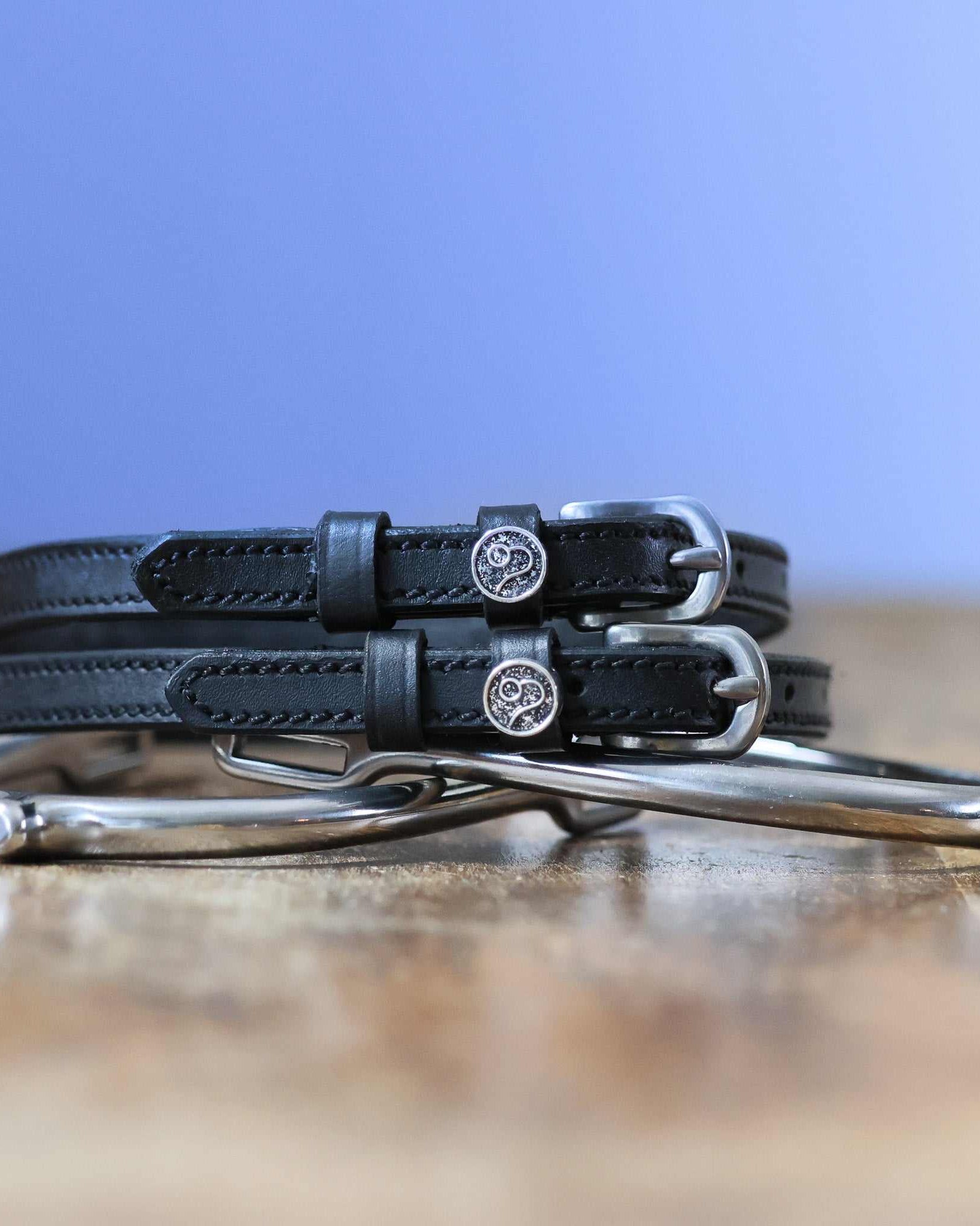 Black leather Leo Spur Straps with stainless steel buckles, custom charms, and durable non-stretch interior, 18 inches long