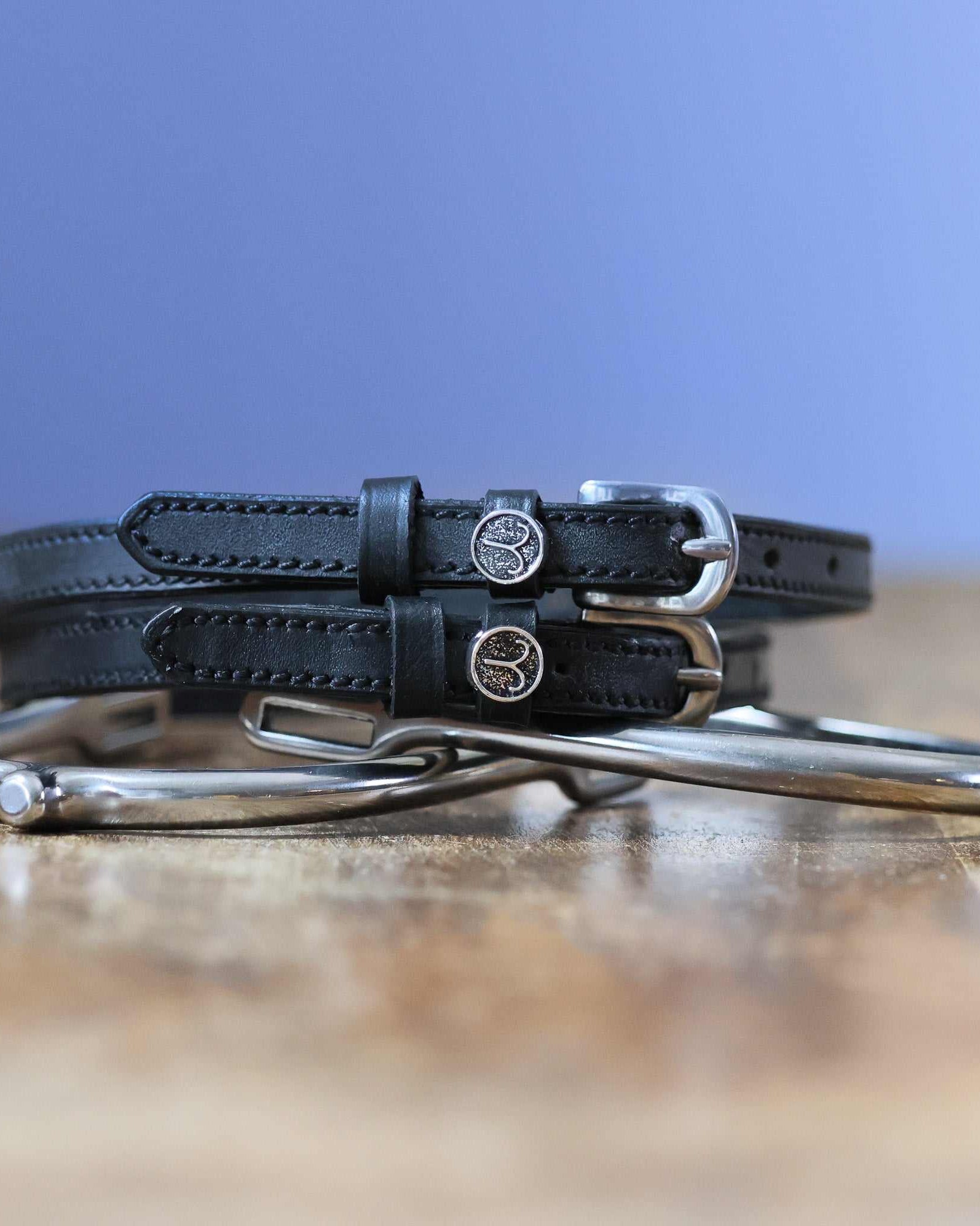Black leather Aries Spur Straps with stainless steel buckles and custom ManeJane charm
