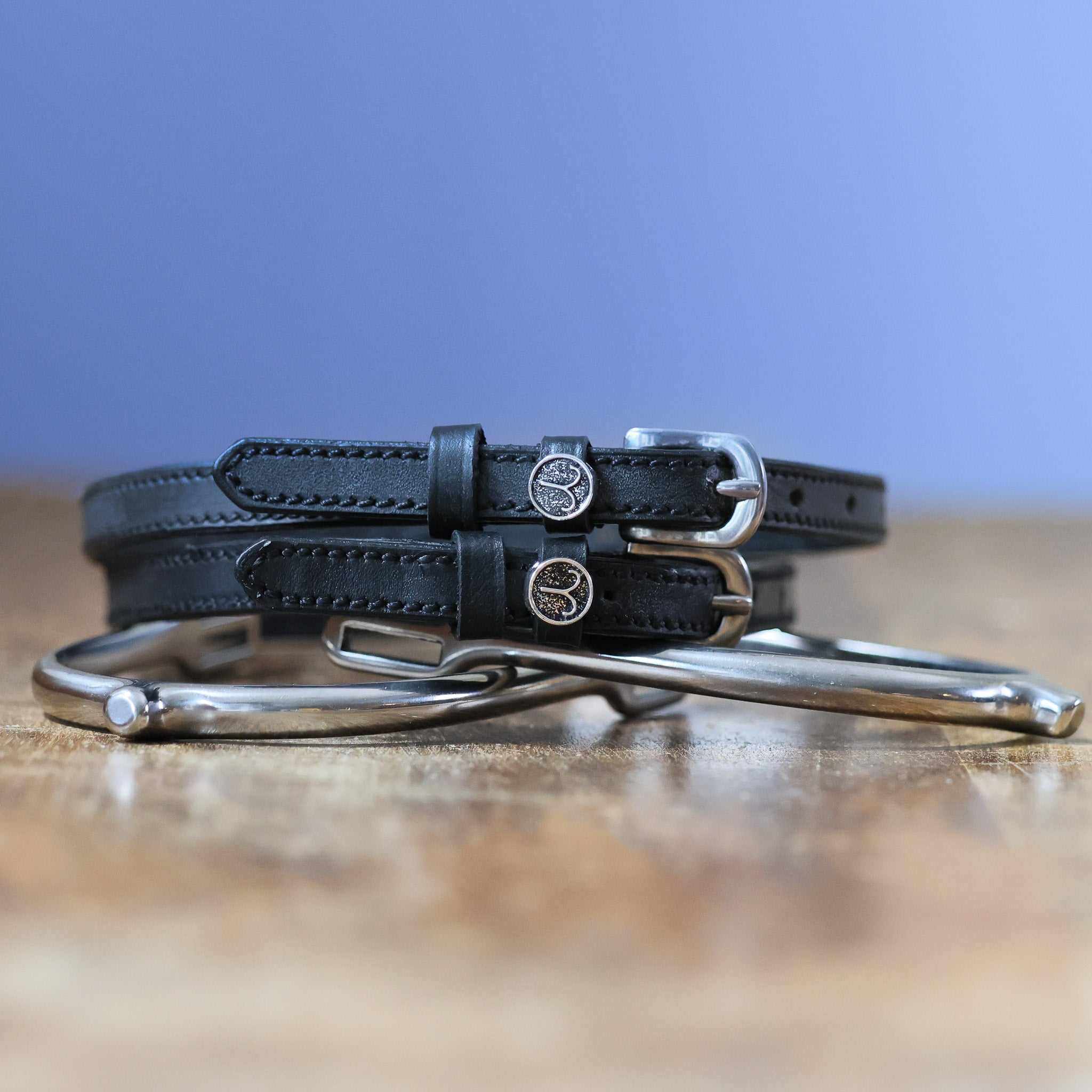 Black leather Aries Spur Straps with stainless steel buckles and custom ManeJane charm
