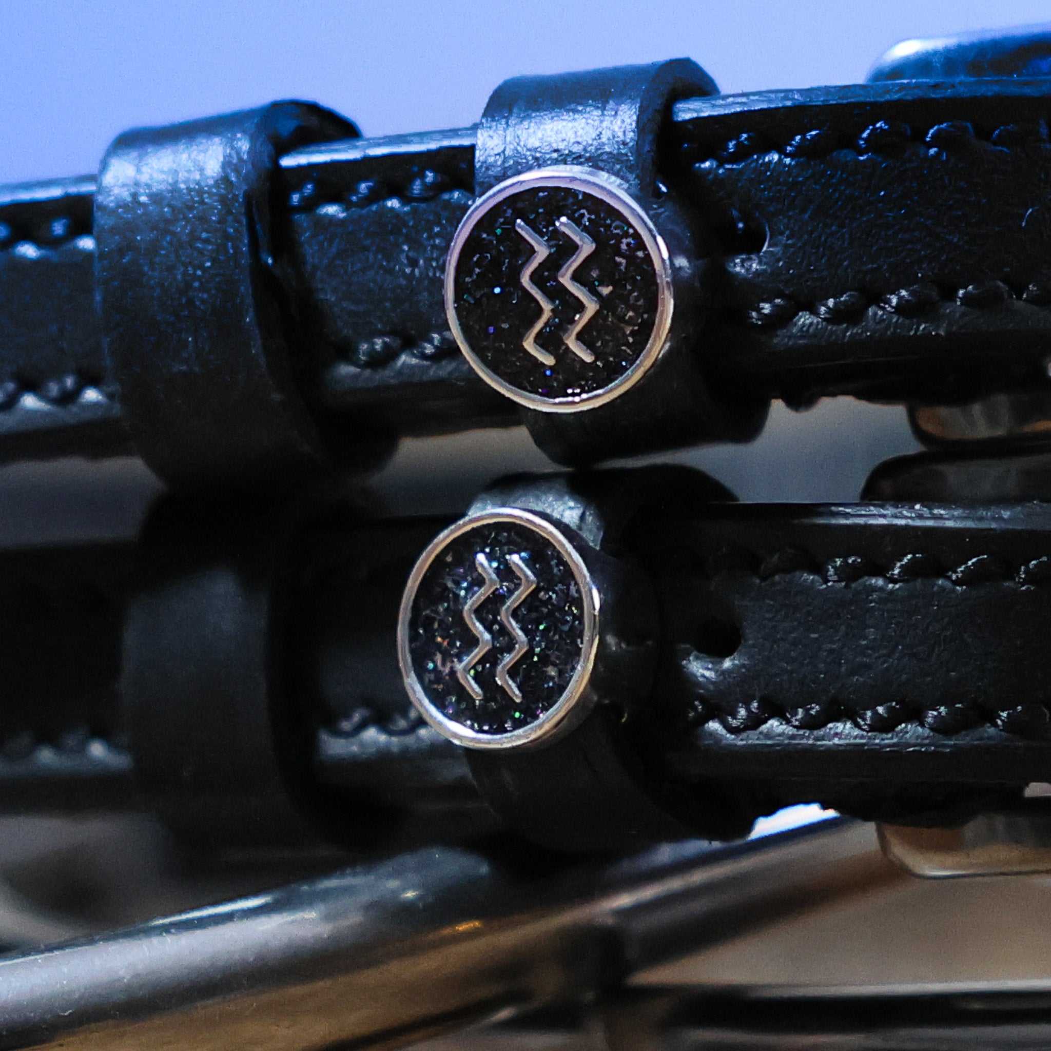 Close-up of black leather Aquarius Spur Straps with stainless steel Aquarius zodiac charm and buckle