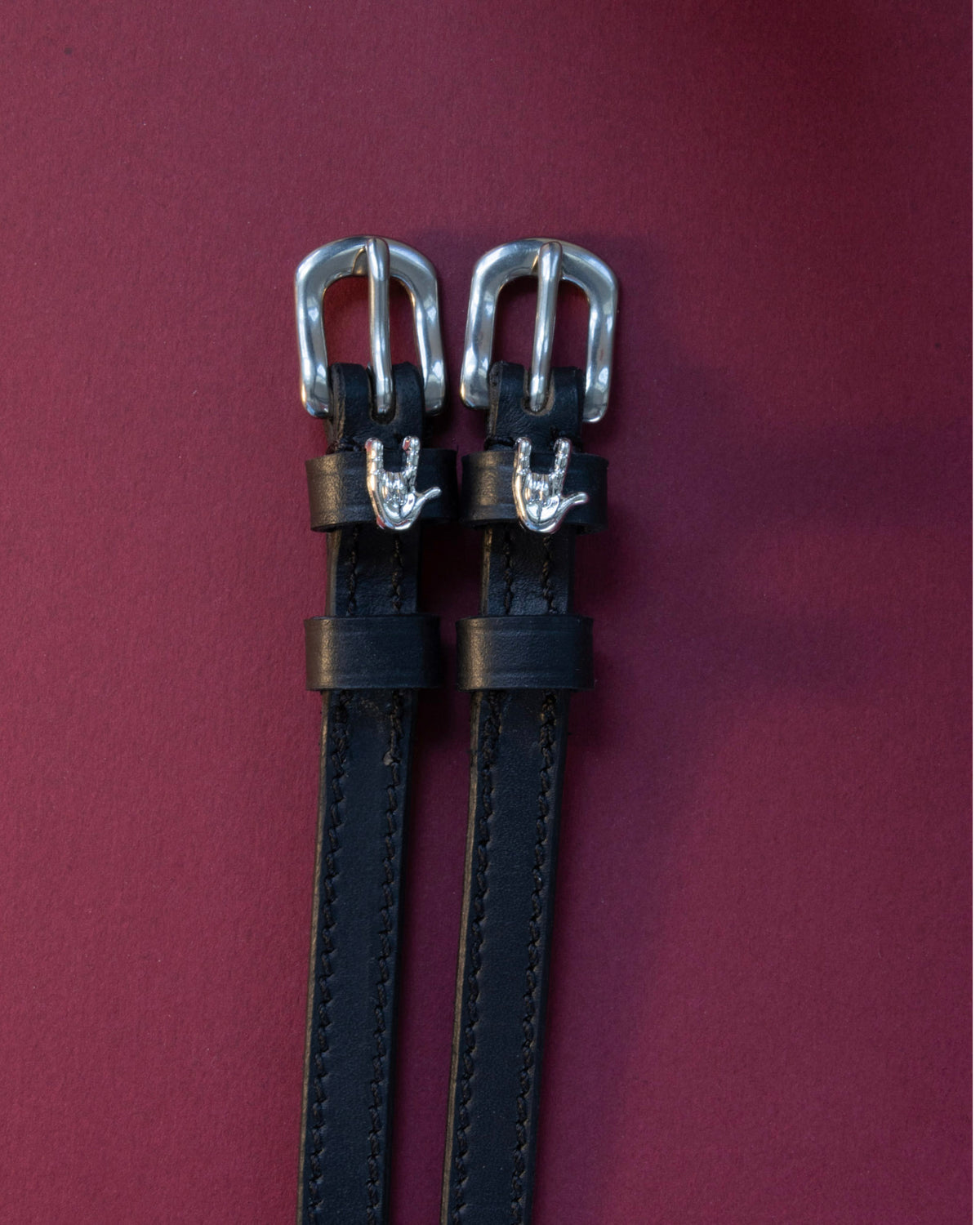 Rock On ManeJane spur straps with the signature Rock On charm, shown on a plum background