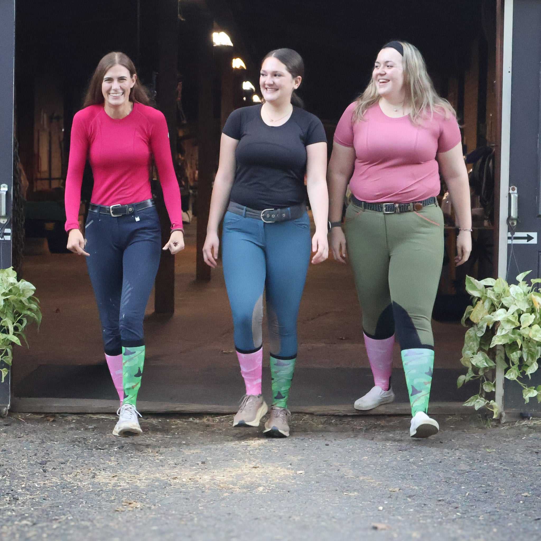 Three women walking wearing colorful boot socks with camouflage patterns at the bottom, paired with casual outfits outdoors
