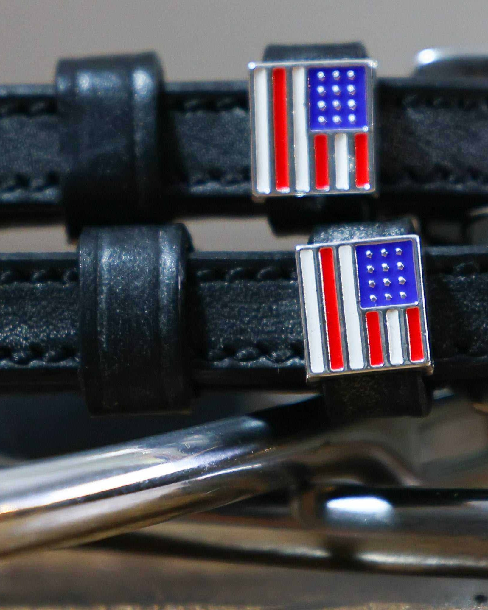Close-up of enamel American flag charms on black leather spur strap keepers
