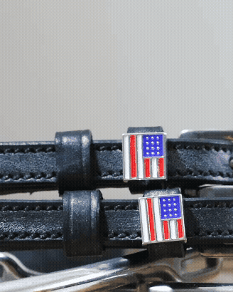 Close-up of American flag charms and silver buckles on black leather spur straps