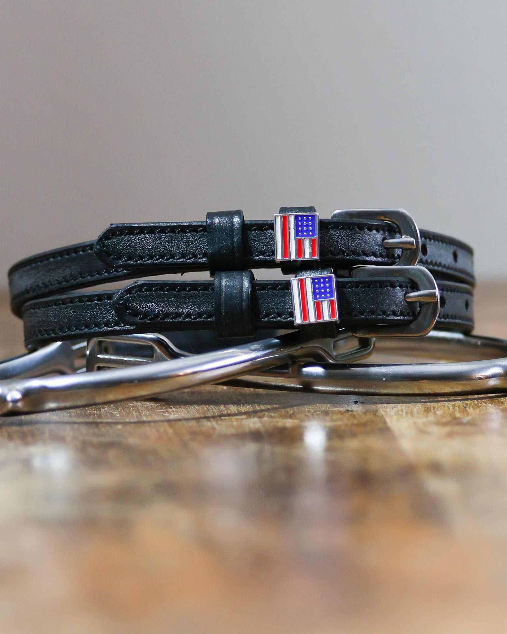 Coiled black leather spur straps and a silver spur on wood with US flag charms