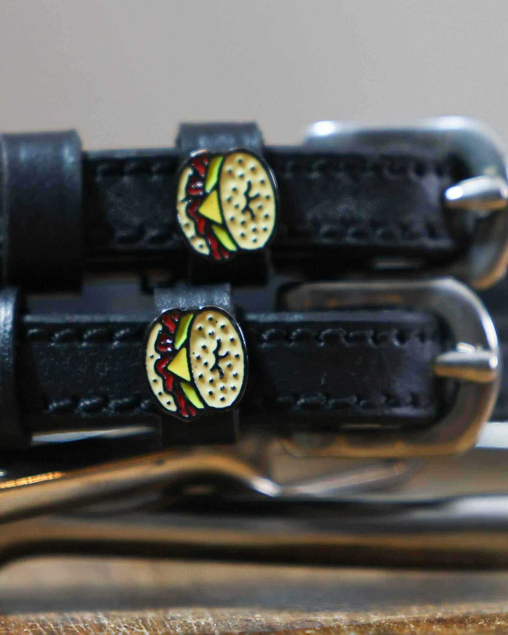 Close-up of an egg bagel sandwich charm on a black leather spur strap keeper