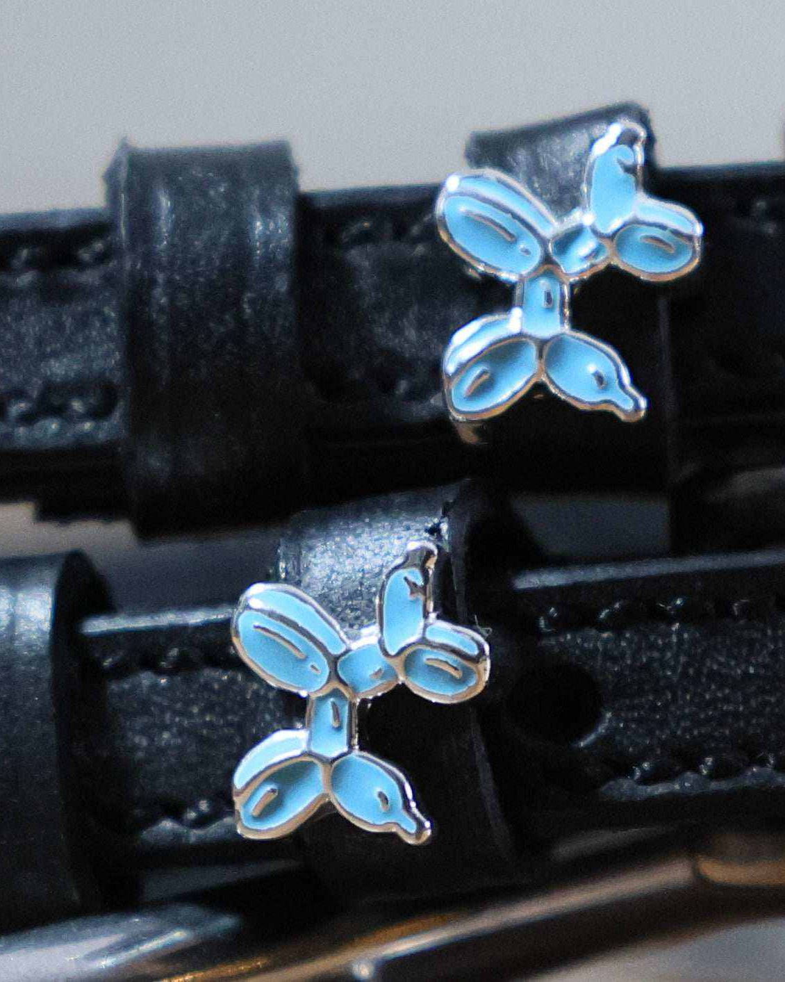 Close-up of blue balloon dog charms on black leather ManeJane spur straps
