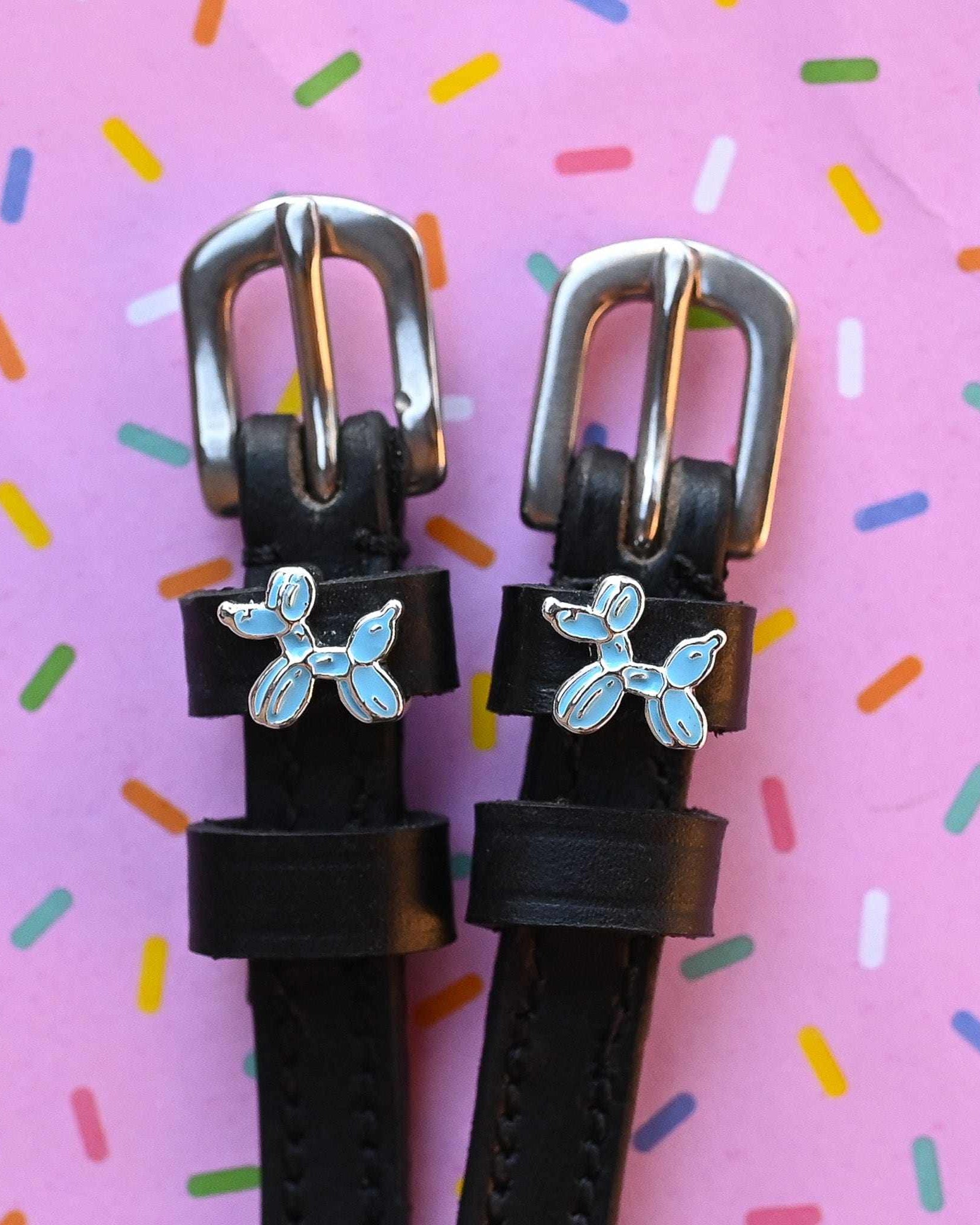 Balloon dog spur straps in black leather on a pink sprinkle confetti background