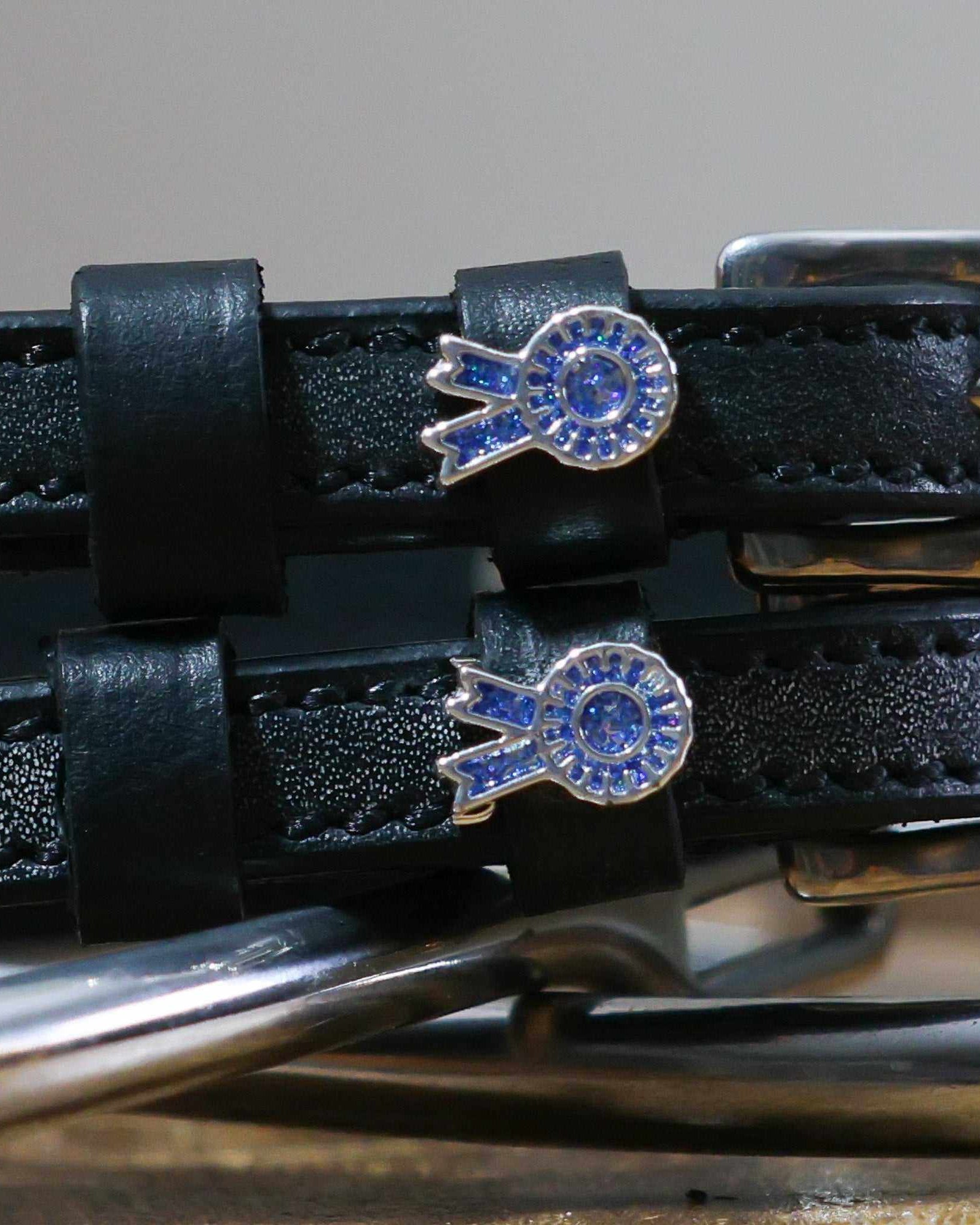 Close-up of blue rosette ribbon charms on black leather spur strap keepers