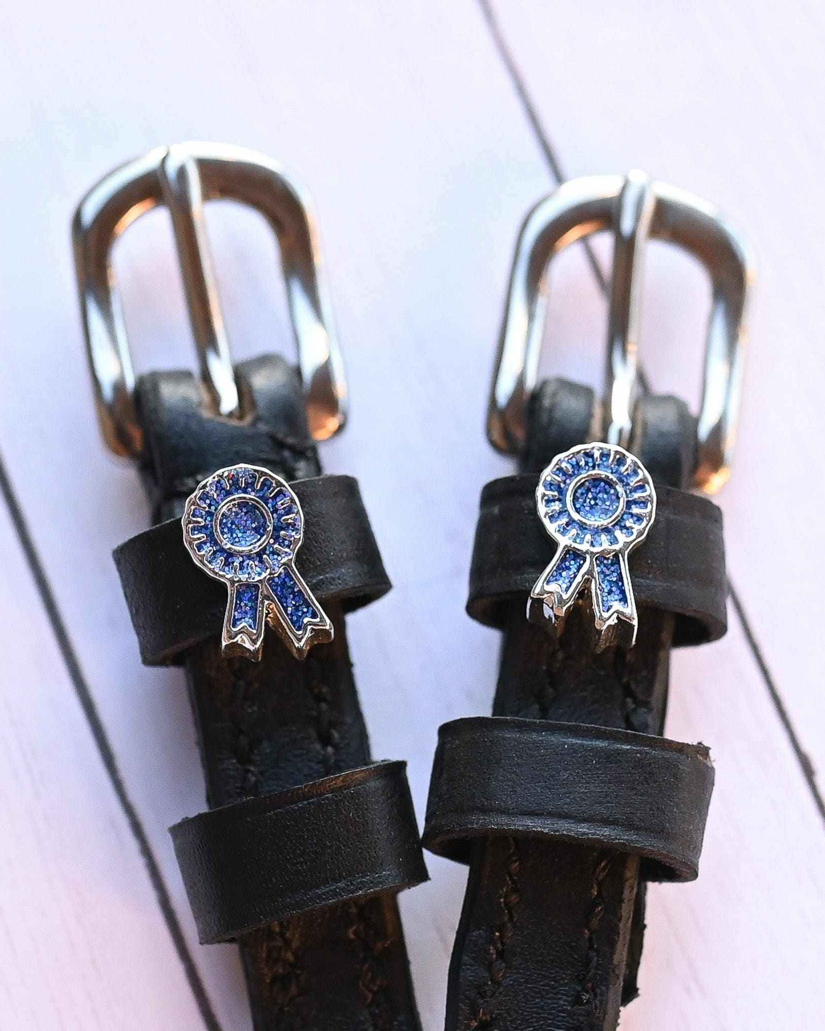 Blue ribbon rosette spur straps with silver buckles on white-painted wood planks