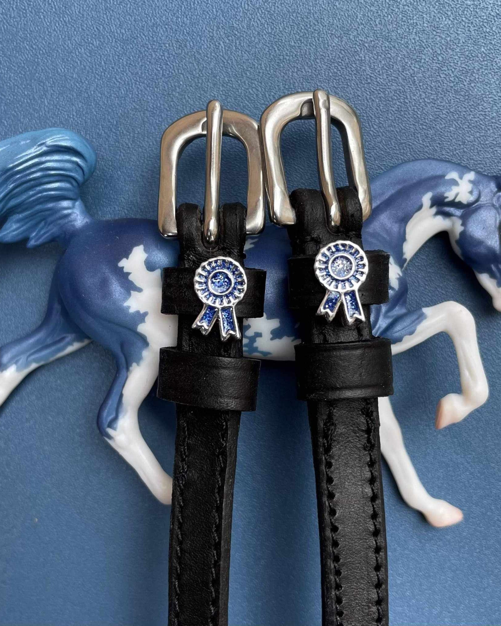 Blue rosette spur straps posed with a blue model horse figurine