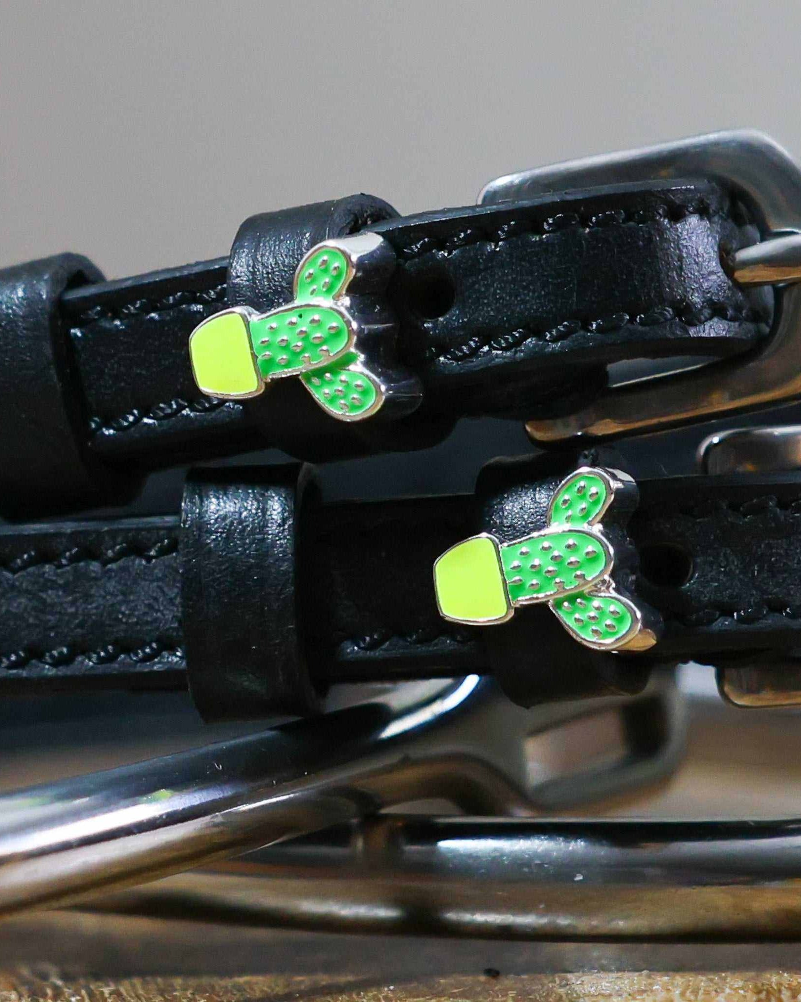 Close-up of potted cactus charms on black leather ManeJane spur strap keepers