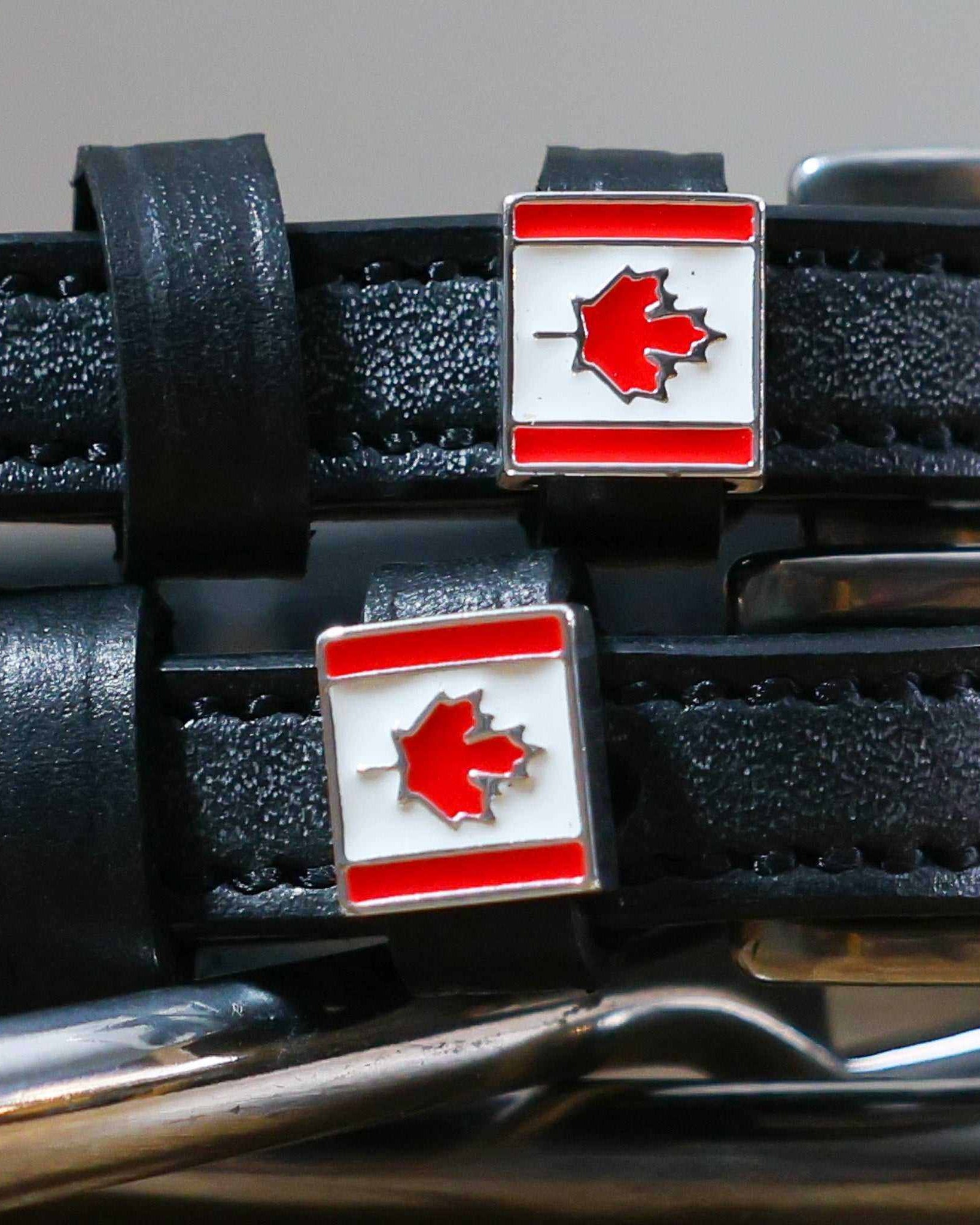 Close-up of Canadian maple-leaf flag charms on black leather ManeJane spur strap keepers