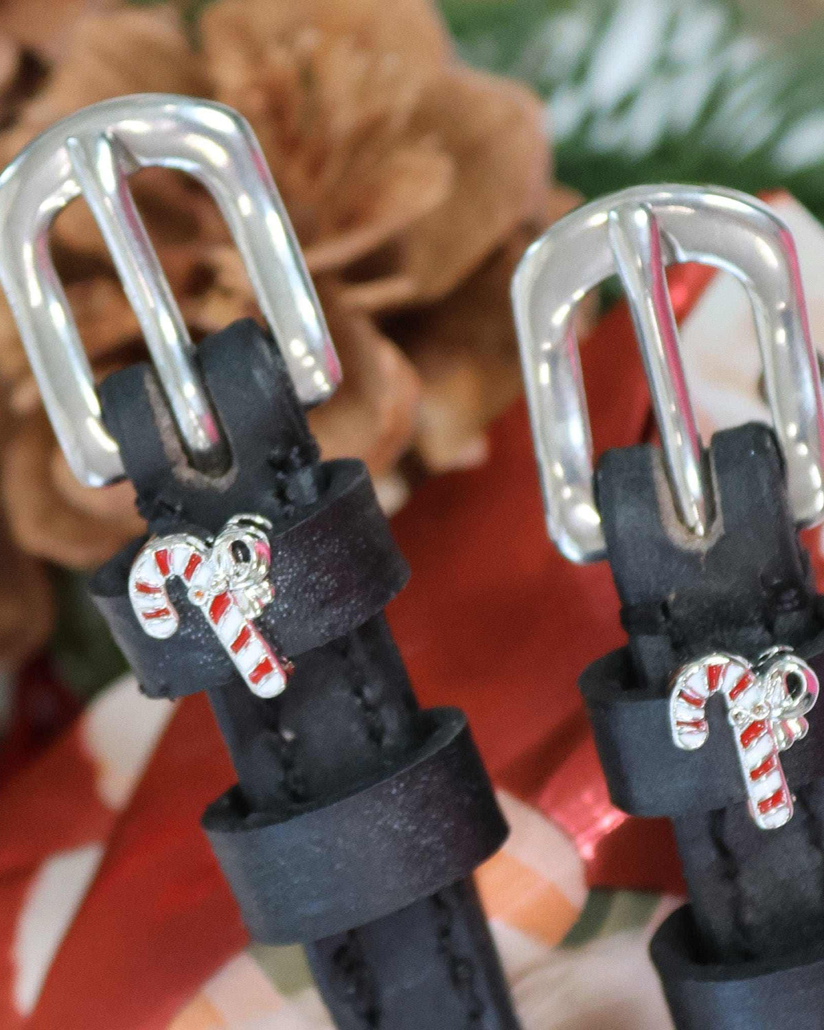 Candy cane charm spur straps styled with pinecones and greenery in a festive scene