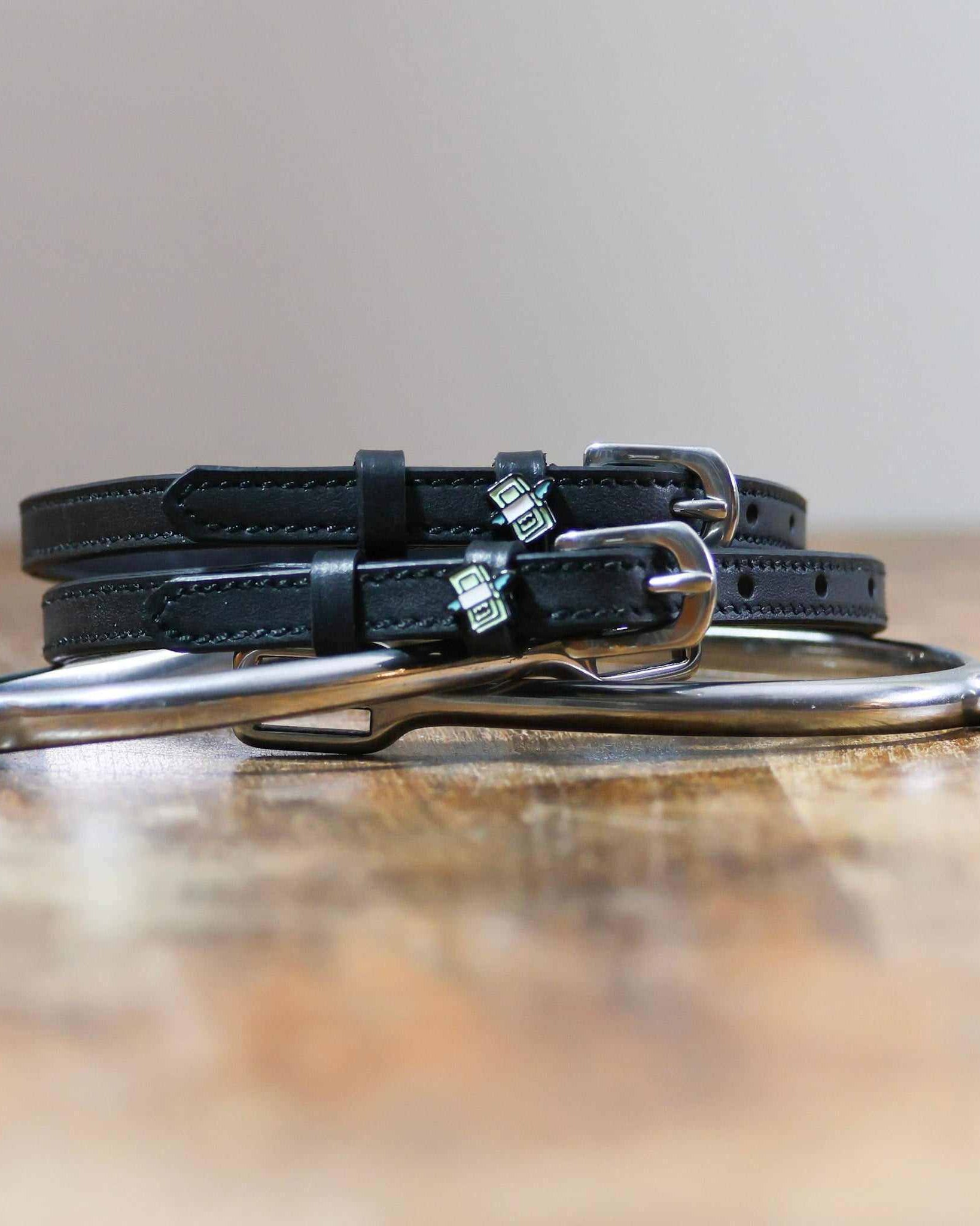 Black leather cash money spur straps coiled beside a spur on wood