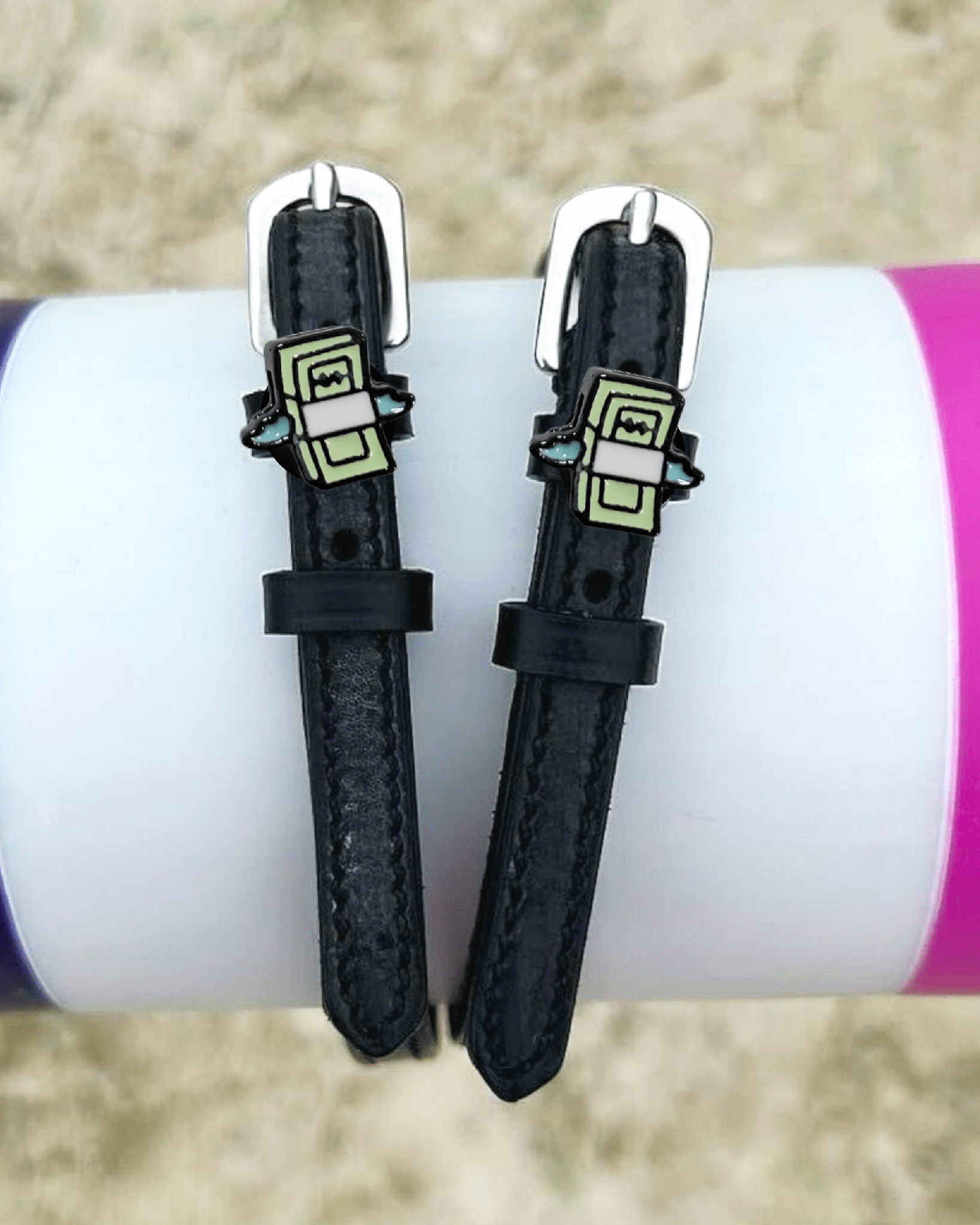 Cash money spur straps draped over a purple and pink jump pole outdoors