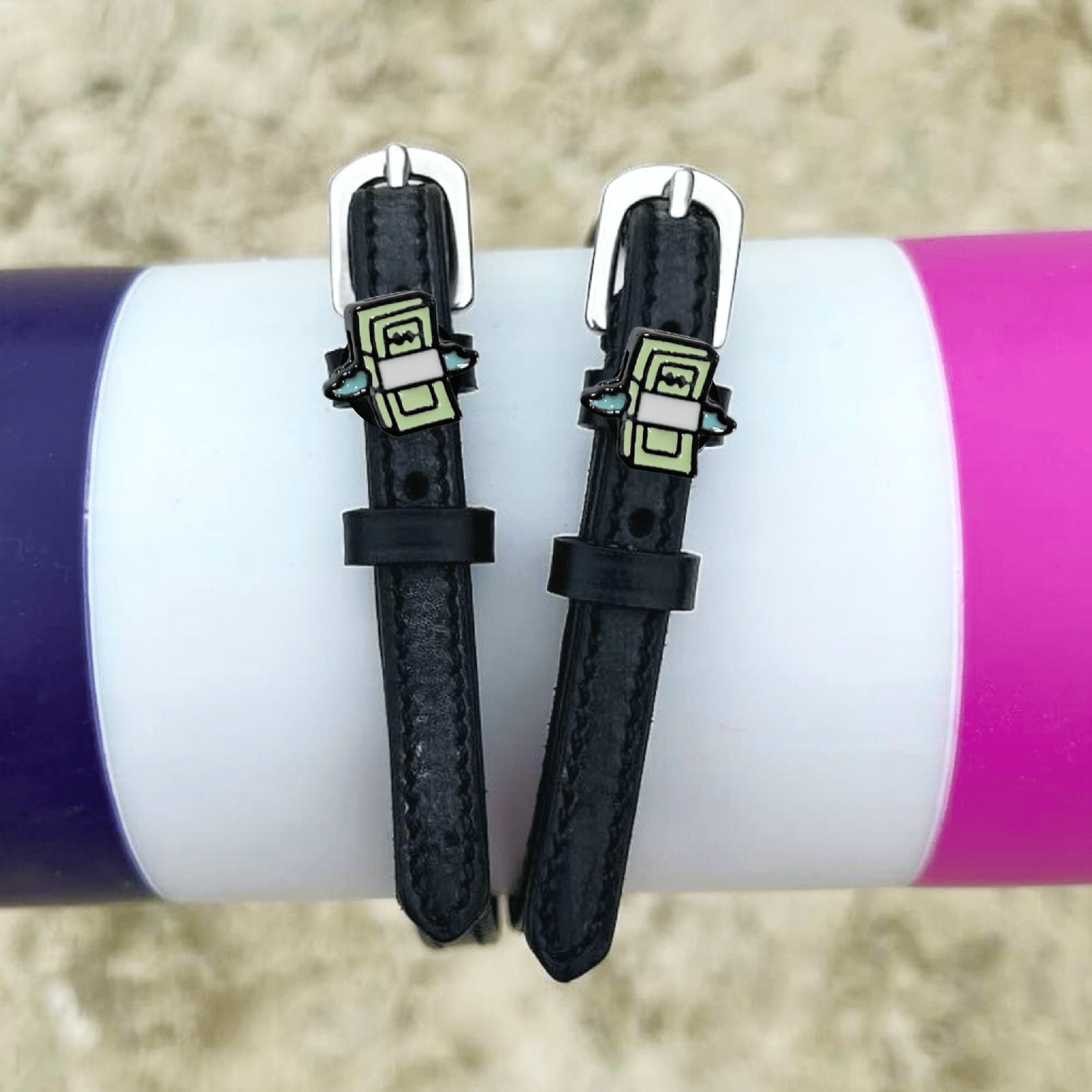 Cash money spur straps draped over a purple and pink jump pole outdoors