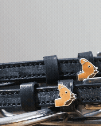 Close-up of chestnut horse-head charms on black leather spur strap keepers