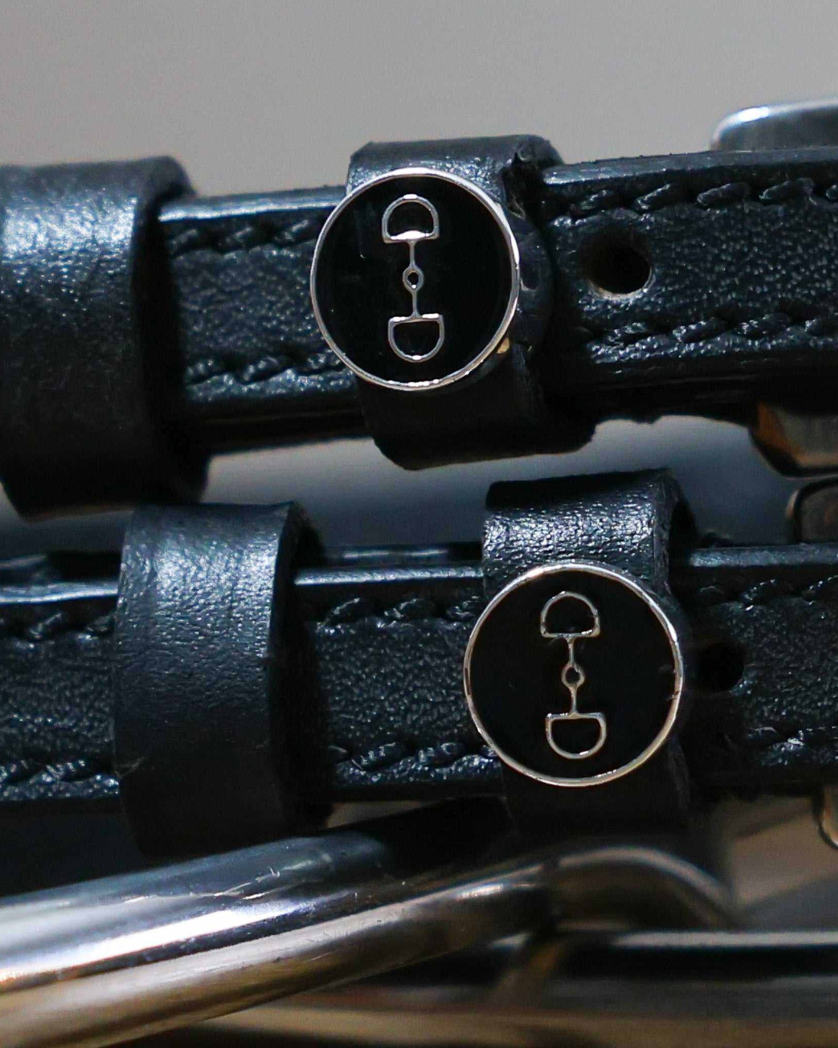 Close-up of black enamel D-ring bit charms on leather spur strap keepers