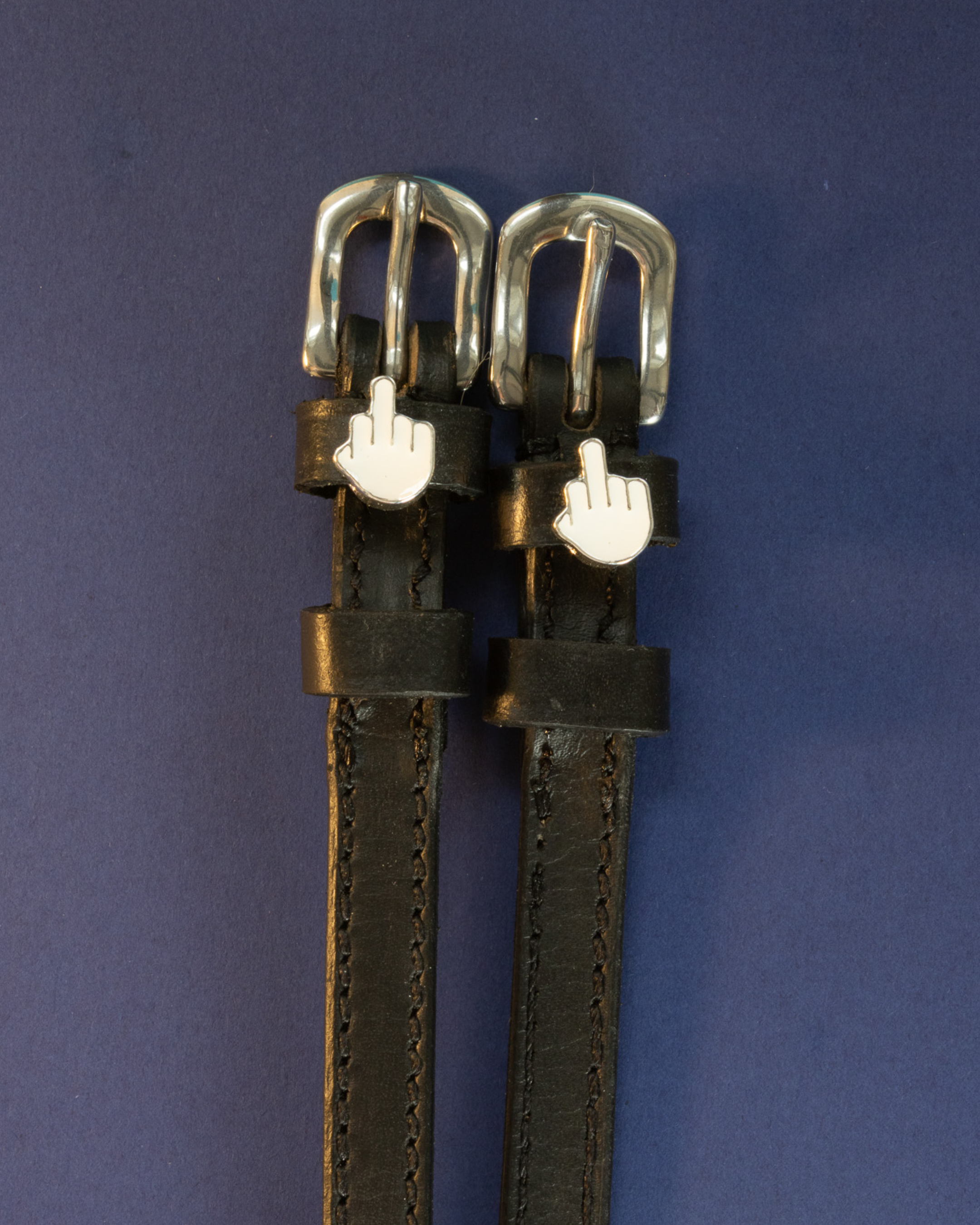 ManeJane Da Bird spur straps with silver buckles and middle-finger emoji charms on a navy background