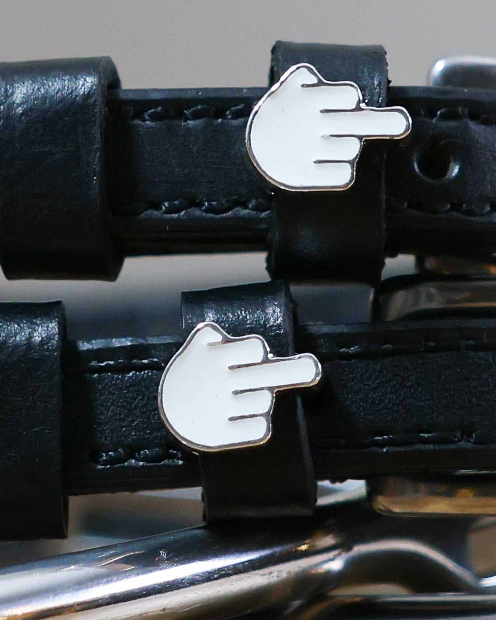 Close-up of white middle-finger emoji charms on black leather ManeJane Da Bird spur strap keepers