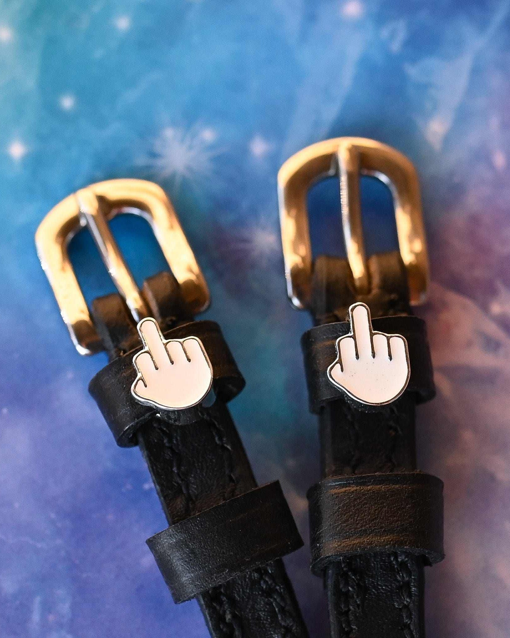 ManeJane Da Bird spur straps with brass buckles and emoji charms on a cosmic galaxy background