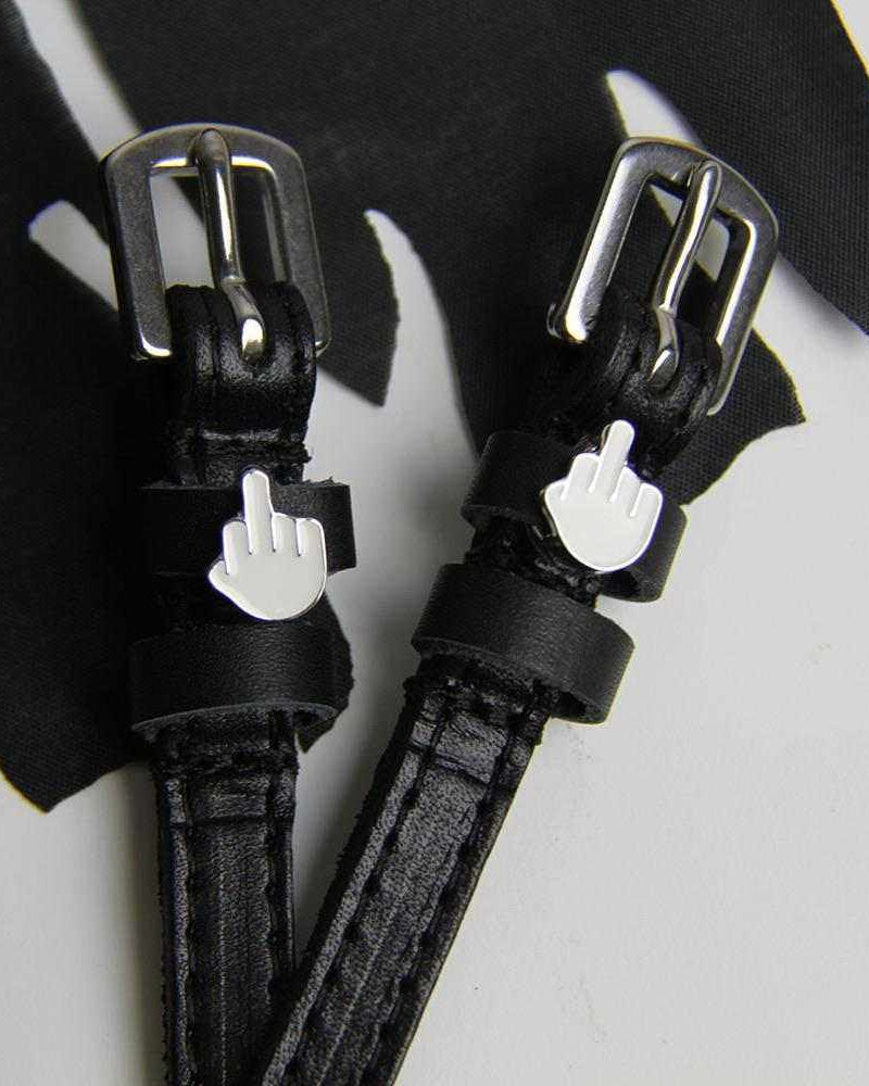 Close-up of black Da Bird spur straps and emoji charms on white with black fabric, ManeJane