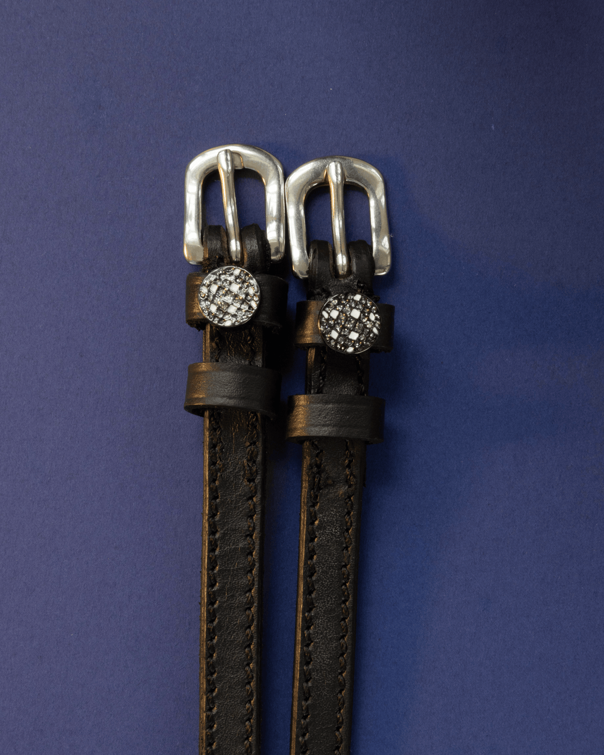 Black leather ManeJane spur straps with sparkling disco ball charms on a navy background