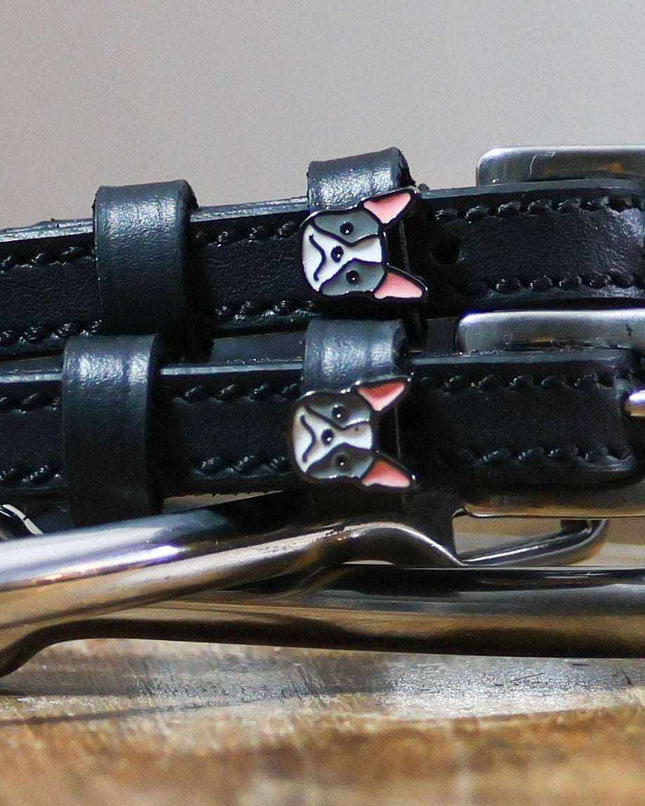 Close-up of French bulldog face charms on black leather spur strap keepers