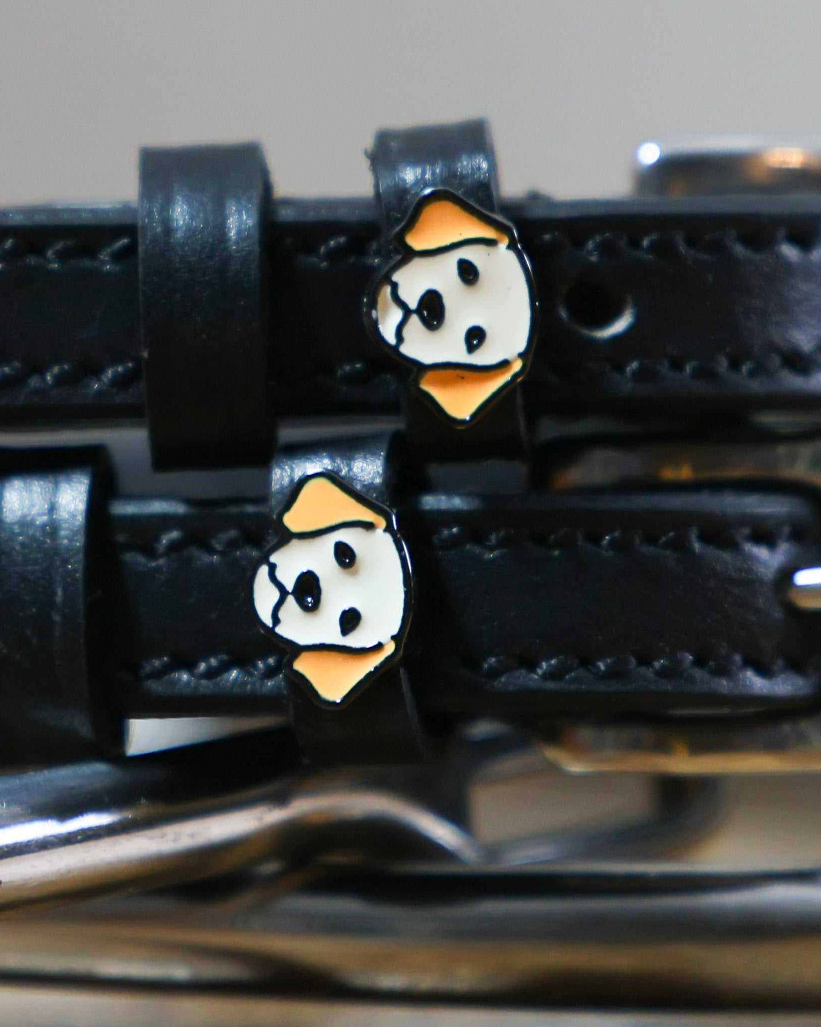 Close-up of golden retriever face charms on black leather spur straps over spur hardware