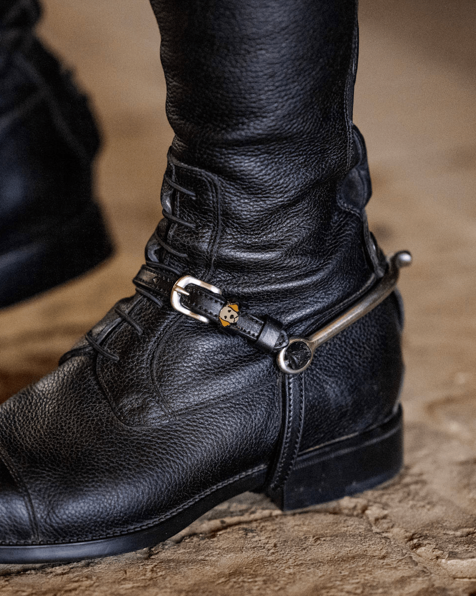 Golden Retriever spur straps fastened on a rider's black English riding boot with spur